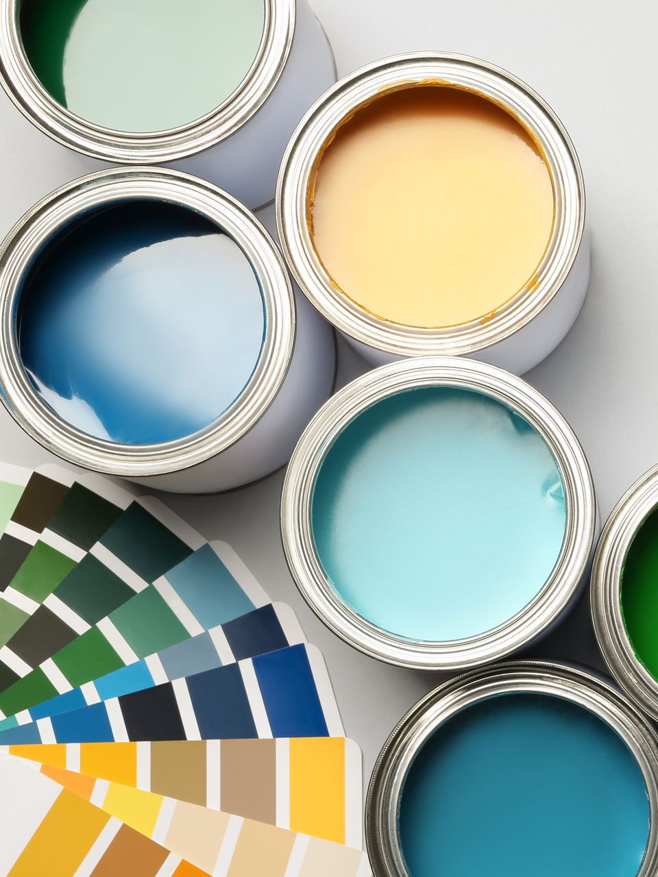 Des pots de peinture aux couvercles ouverts laissant apparaître différentes couleurs et un éventail de couleurs.