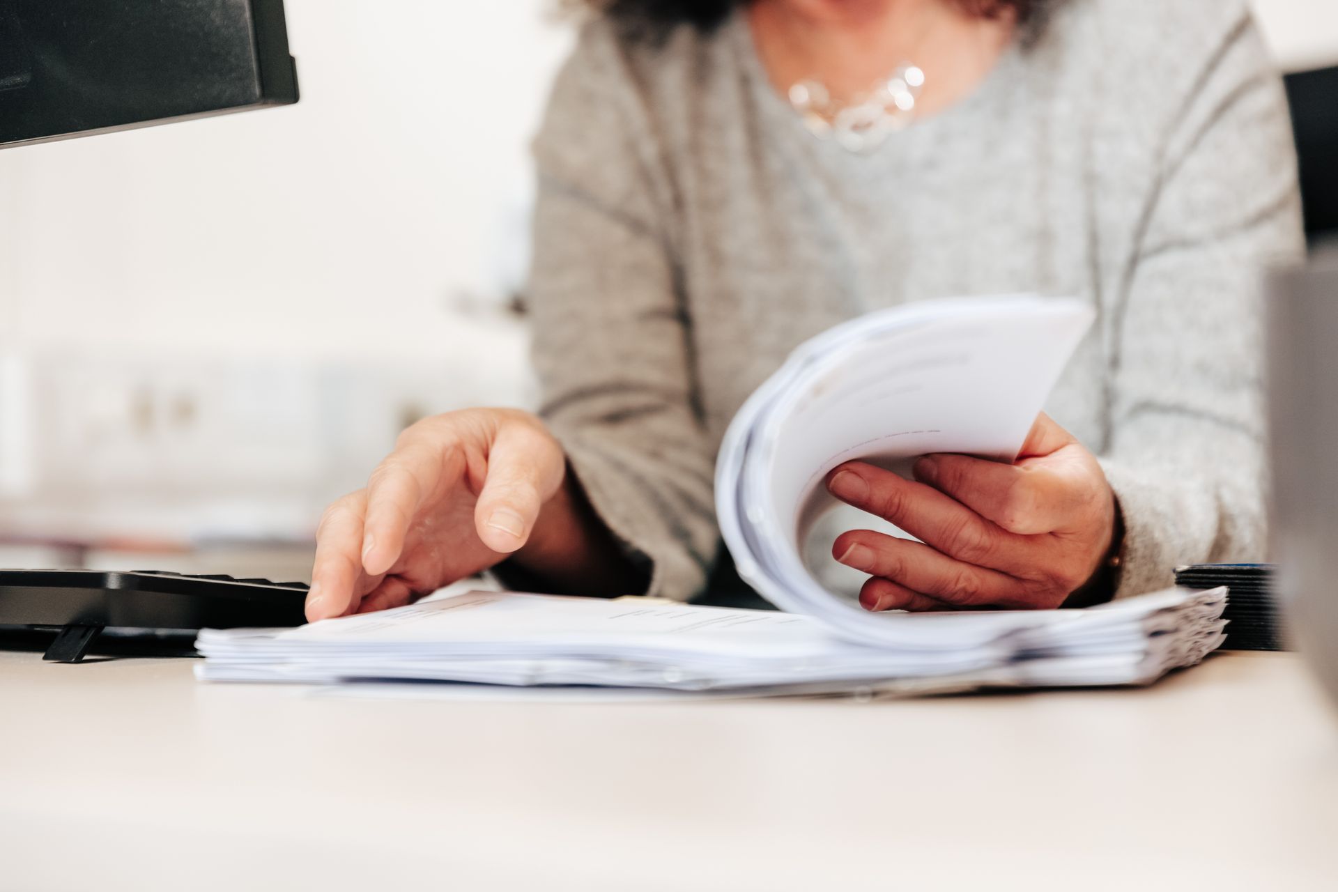 Zwei Personen prüfen Finanzdokumente, eine davon verwendet einen Taschenrechner.