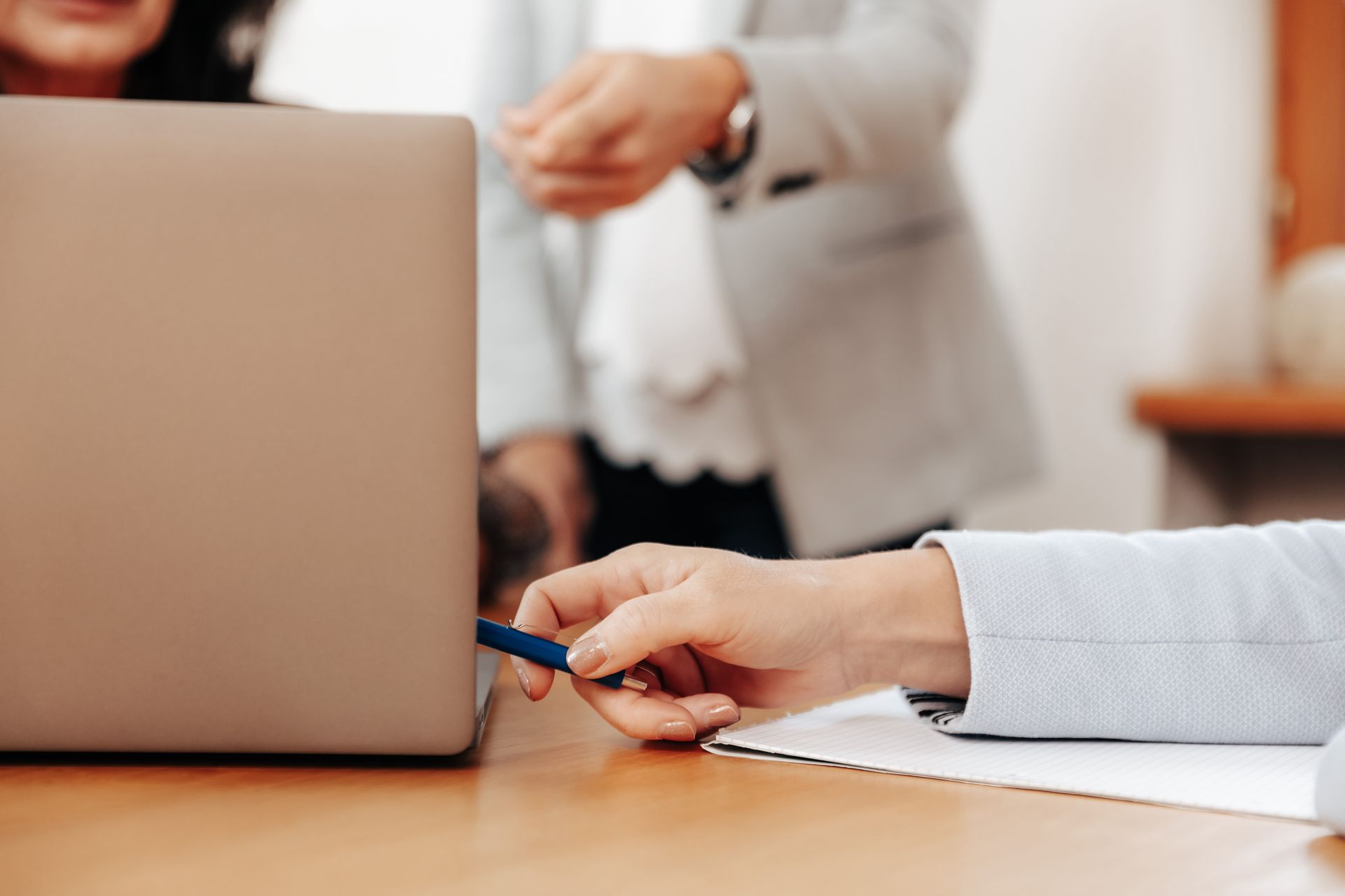 Person, die ein Tablet und einen Laptop mit einem Taschenrechner und einem Notizbuch auf einem Schreibtisch verwendet.