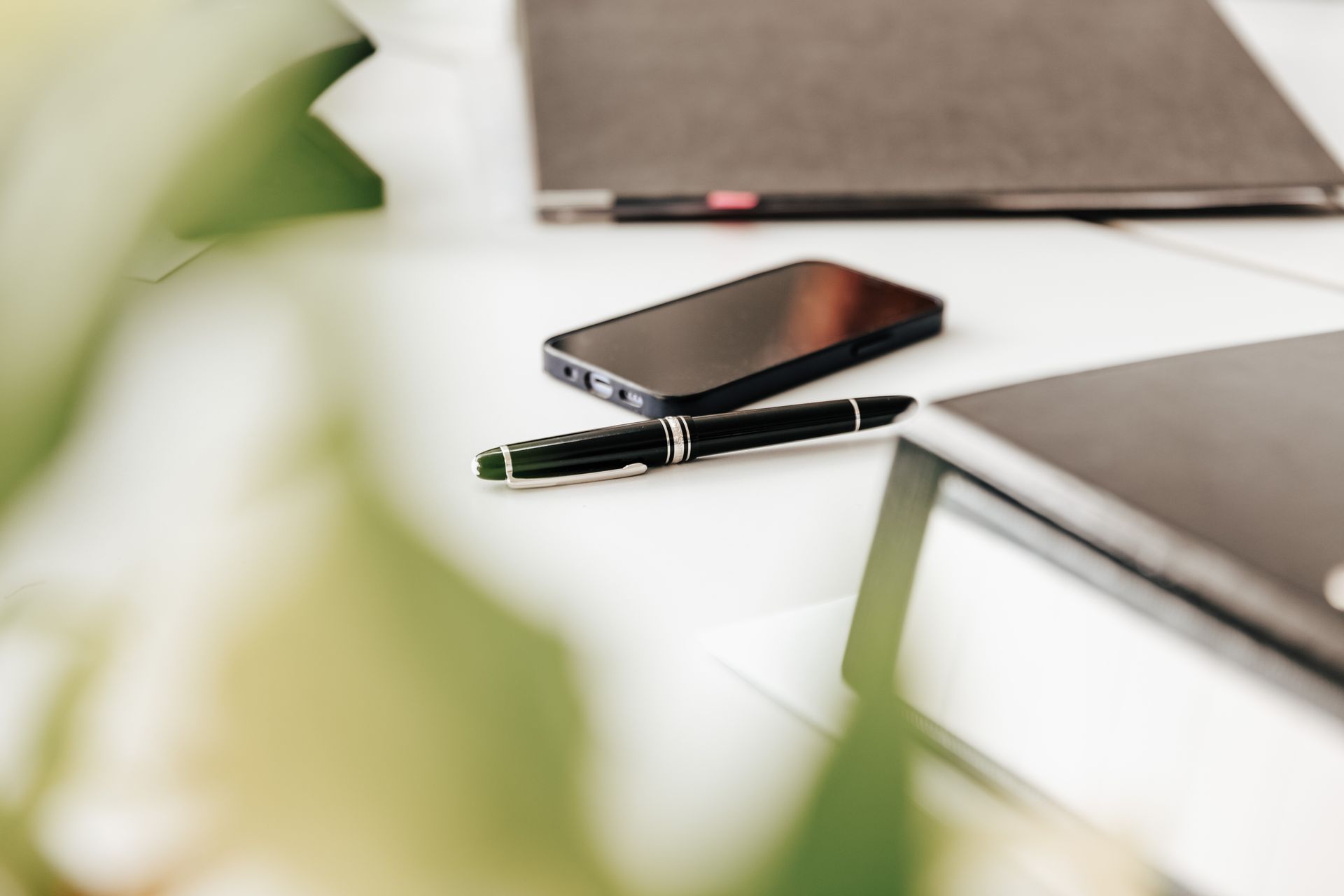 Zwei Personen überprüfen in einem Büro Finanzdaten mithilfe eines Laptops, Diagrammen und eines Taschenrechners.