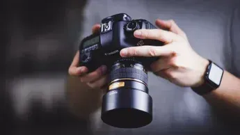 Persona sosteniendo una cámara DSLR, lista para tomar una foto.