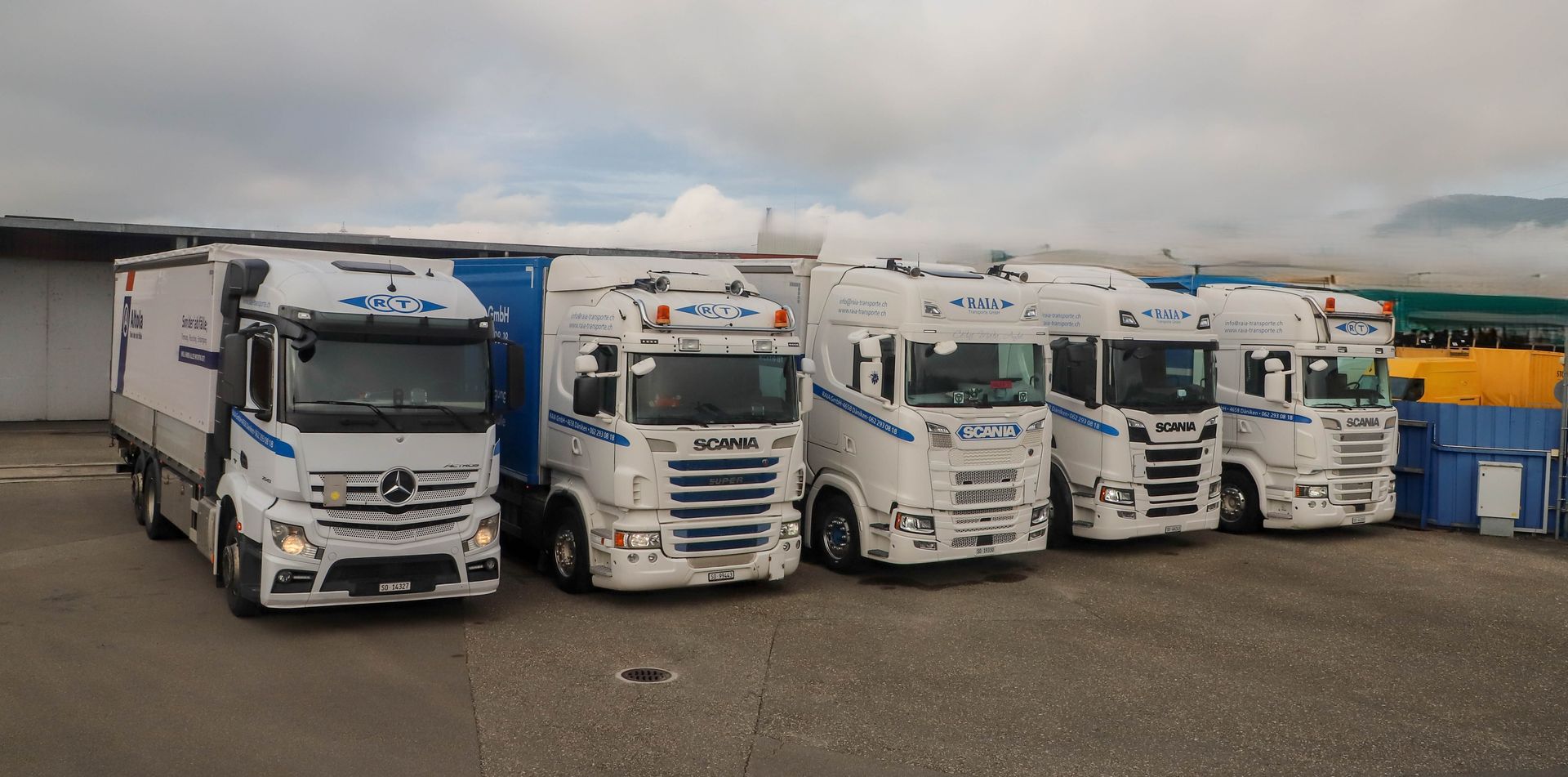 Ein blauer Industriecontainer auf einem gepflasterten Parkplatz vor einem Gebäude.