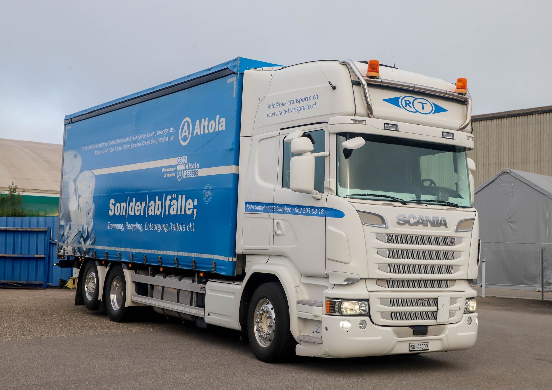 Eine Reihe weisser Sattelschlepper parkte auf einem Betonparkplatz unter einem bewölkten blauen Himmel.