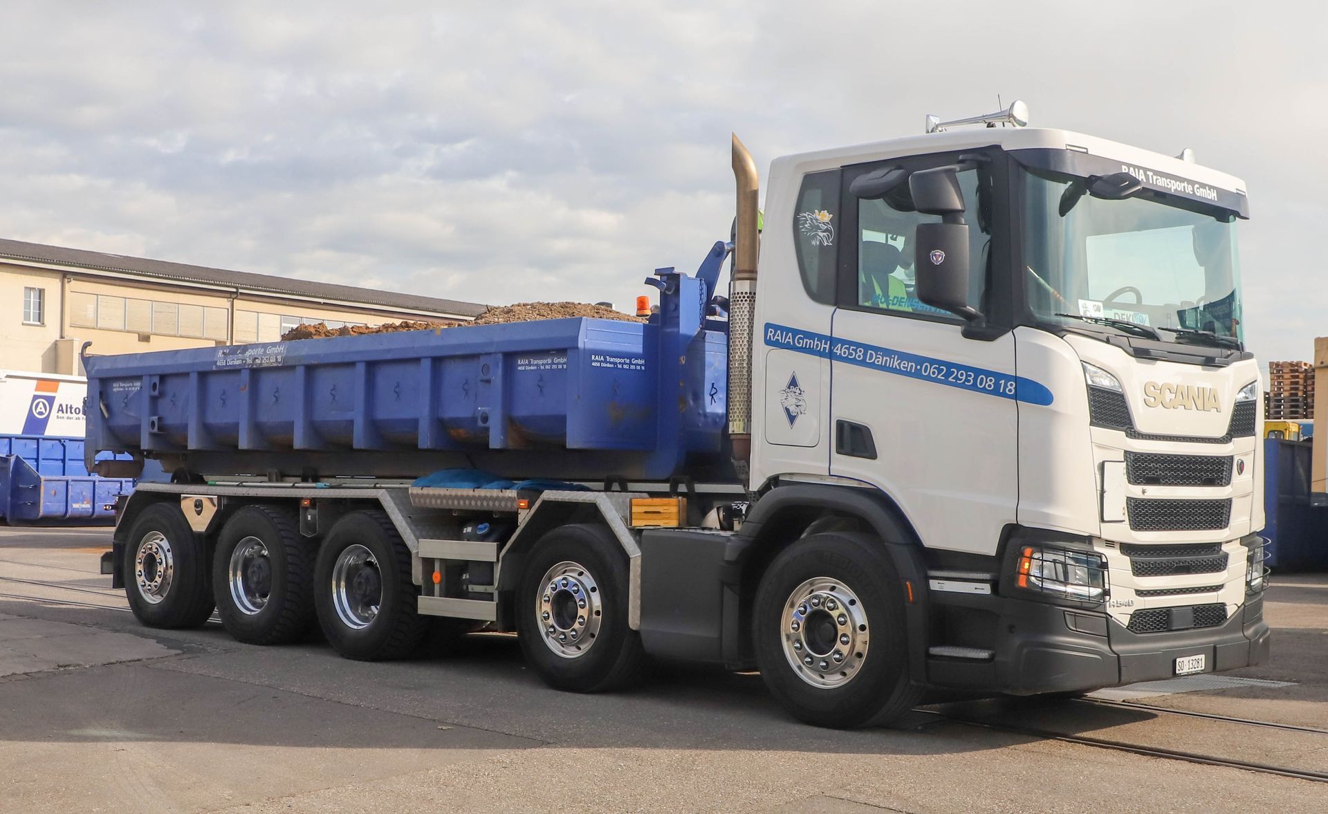 Zwei weisse Scania-Sattelzüge parkten in der Abenddämmerung nebeneinander, der Himmel war in Orange- und Rosatönen gehalten.