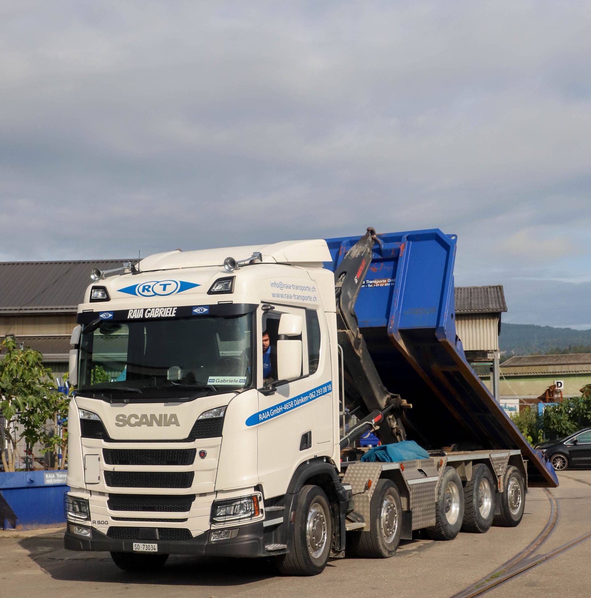 Vier weisse Sattelzüge parkten auf einem grauen Parkplatz unter bewölktem Himmel.