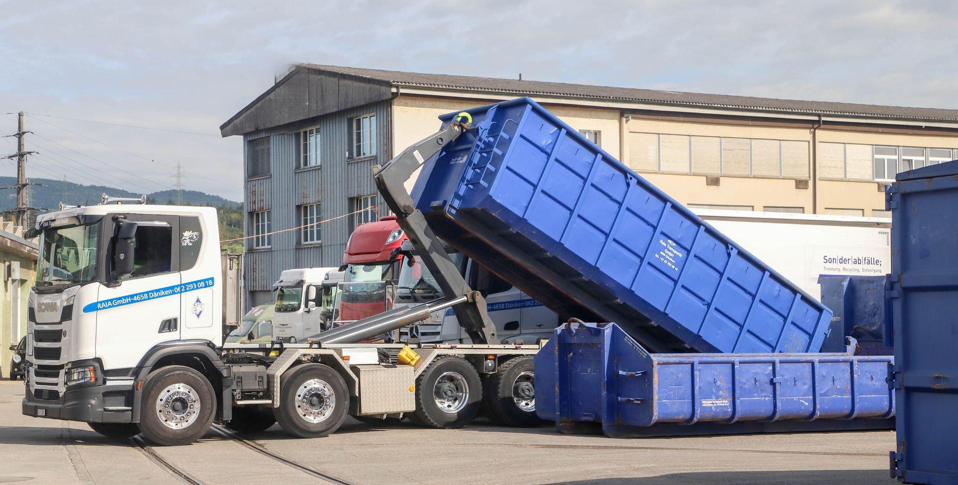Eine Strassenkehrmaschine sammelt Laub und Schmutz von der Strasse. Der Fahrer trägt orangefarbene Schutzkleidung.