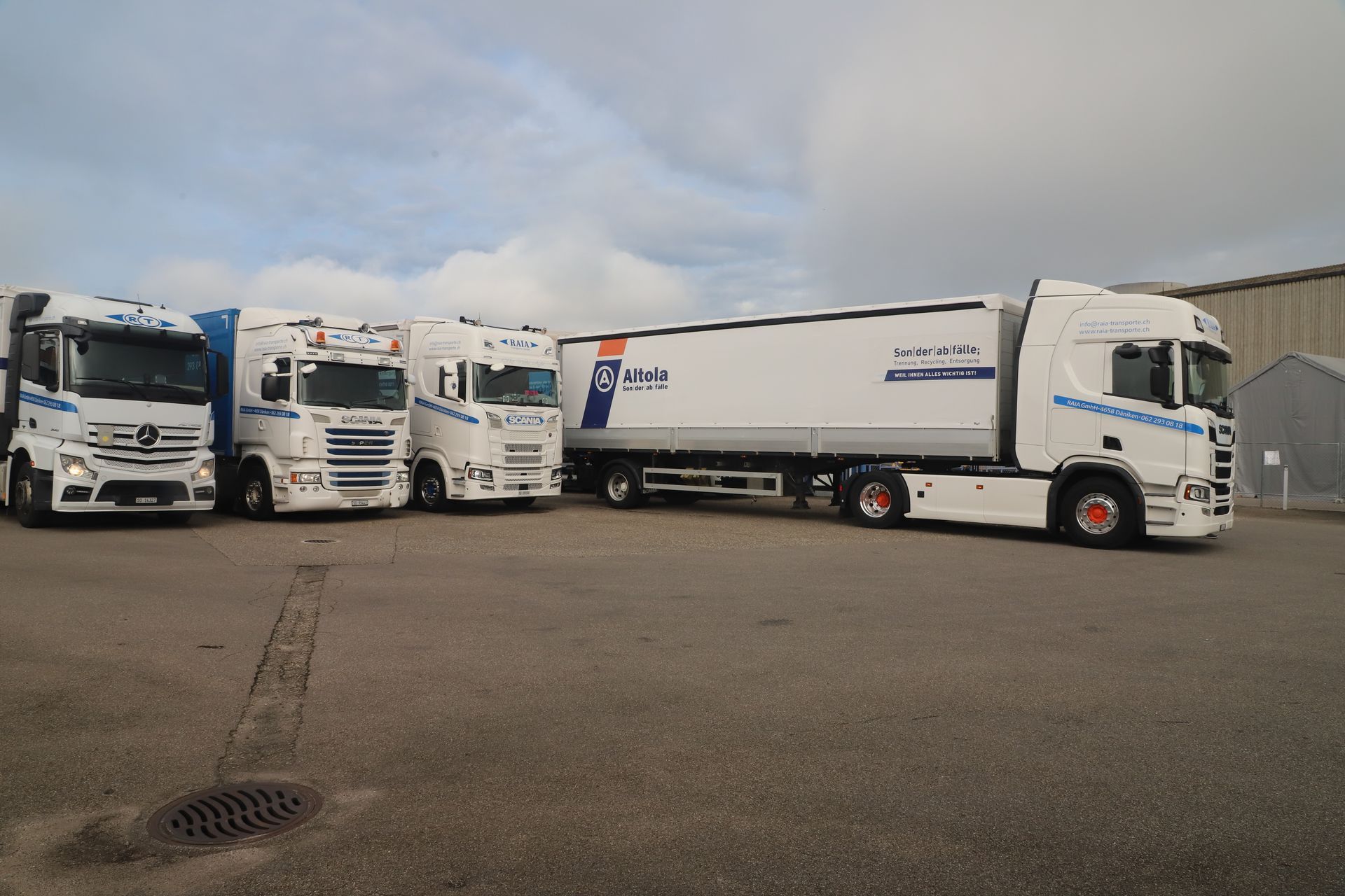 Ein weiss-blauer Scania-Kipper, beladen mit Material, steht im Freien.