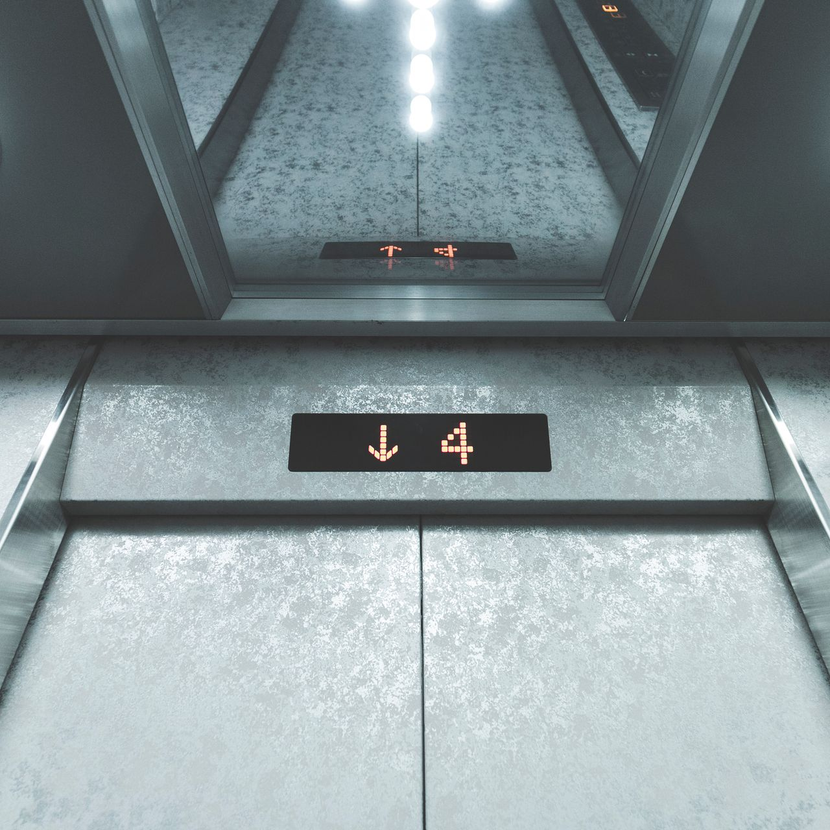 Intérieur de l'ascenseur, murs argentés, descendant jusqu'au 4e étage.
