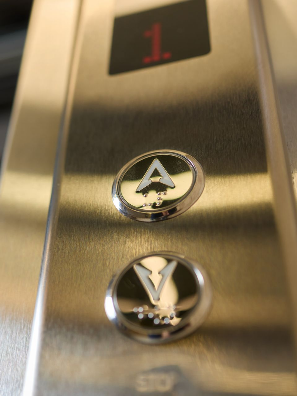 Panneau d'ascenseur avec boutons pour l'étage 1, flèches haut et bas.