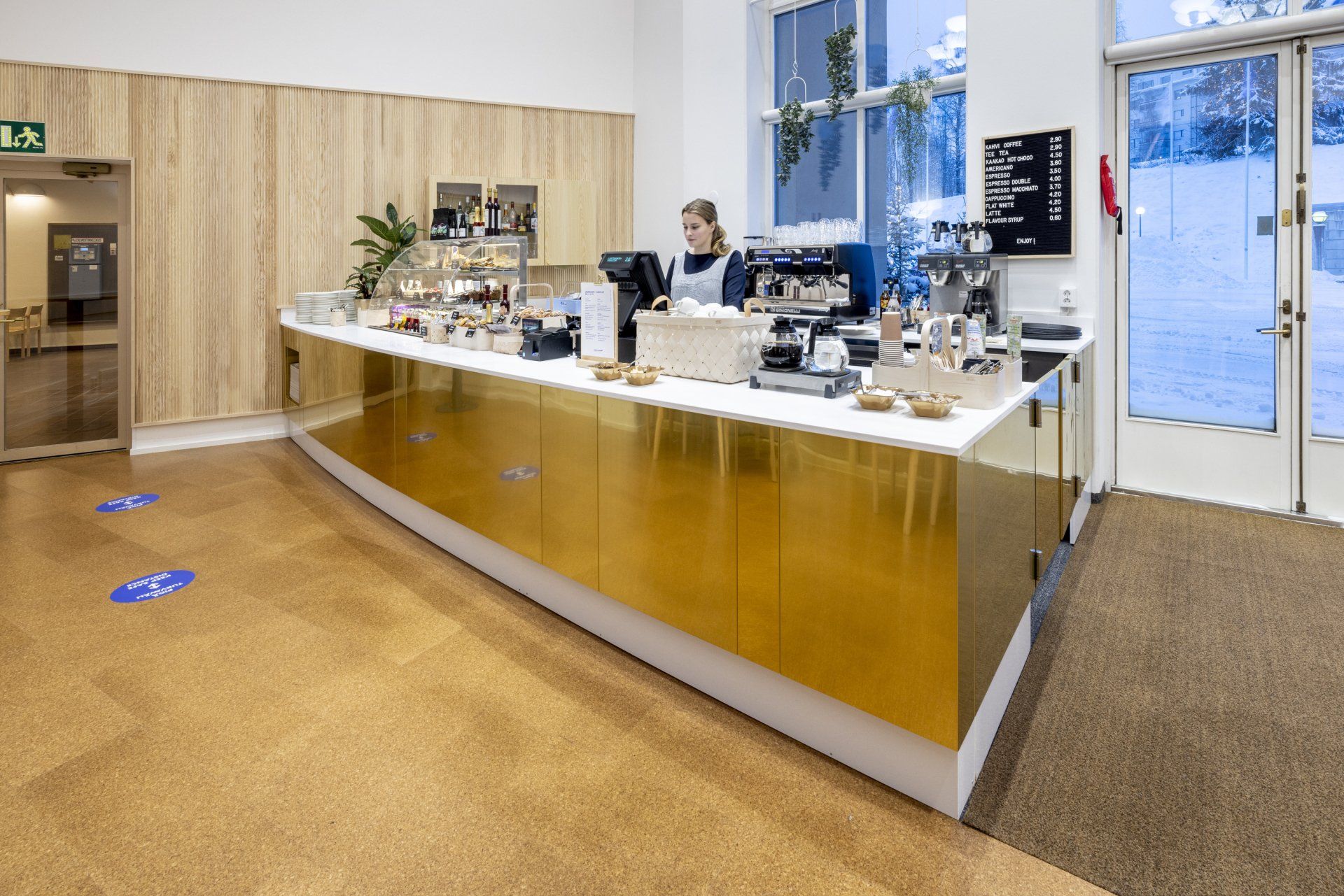 Kahvilan kassa ja tarjoilulinjasto. Tiskin etupinta messinkiä. 