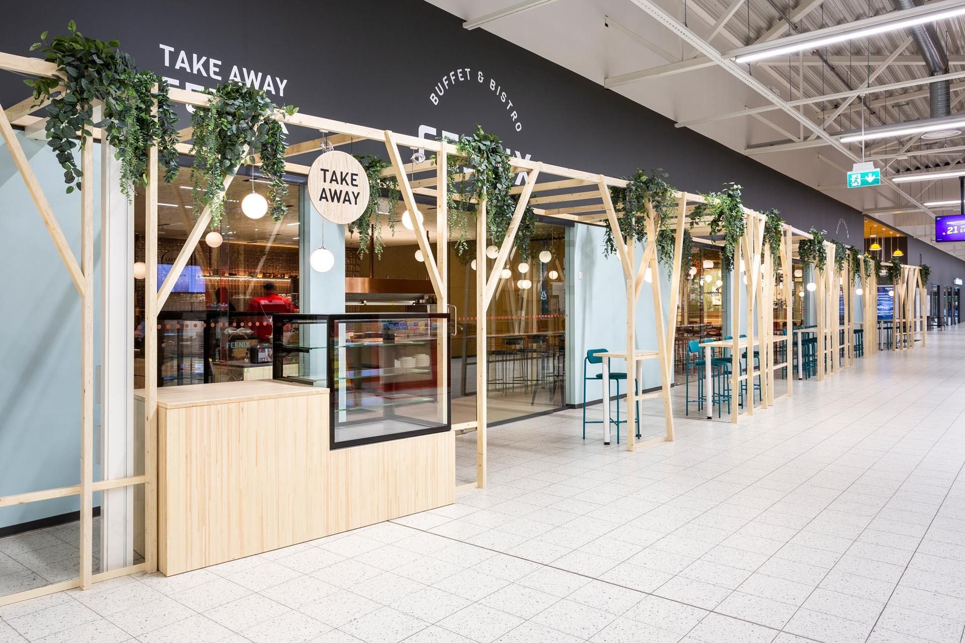 Houkutteleva ravintolan sisäänkäynti kauppakeskuksessa. Viherkatos rimoista. 