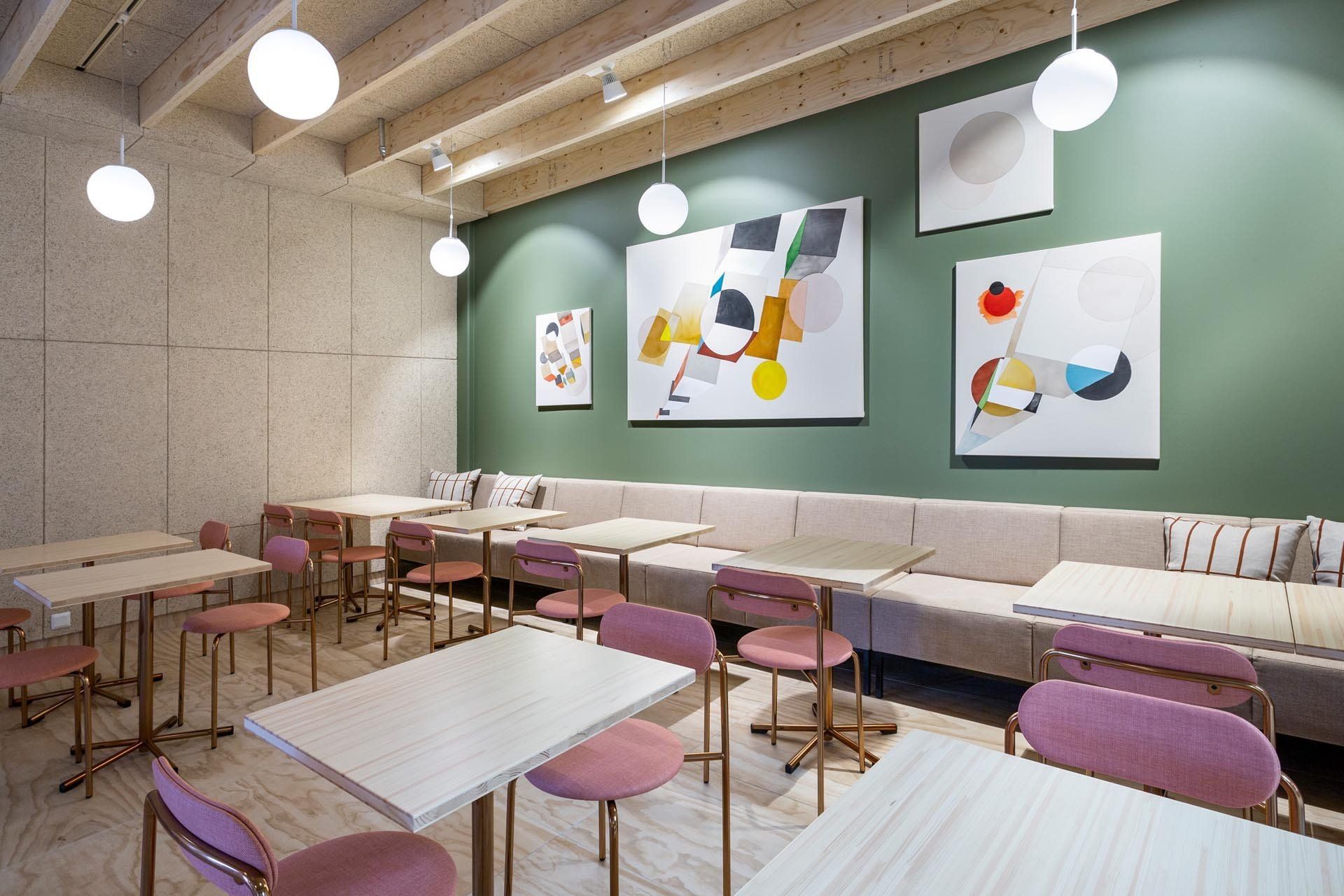 Ravintolan vaaleanpunaiset tuolit Lepo Product Moderno. Seinällä taulut Tuomas Korkalo. Katosta ripustettu pallovalaisimet.