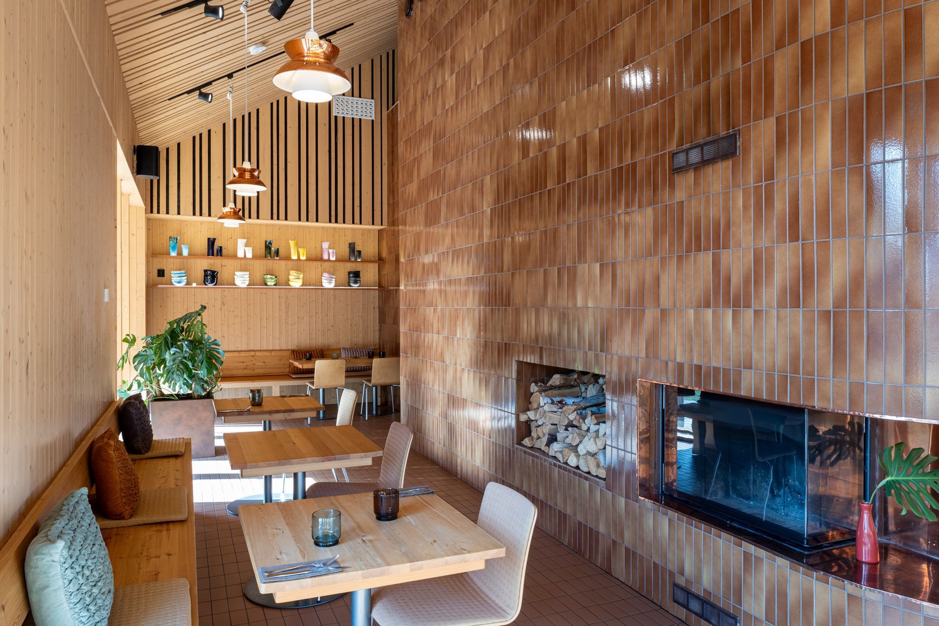 Laatoitettu takkaseinä ja rytmitetty rimaseinä ravintolassa. 