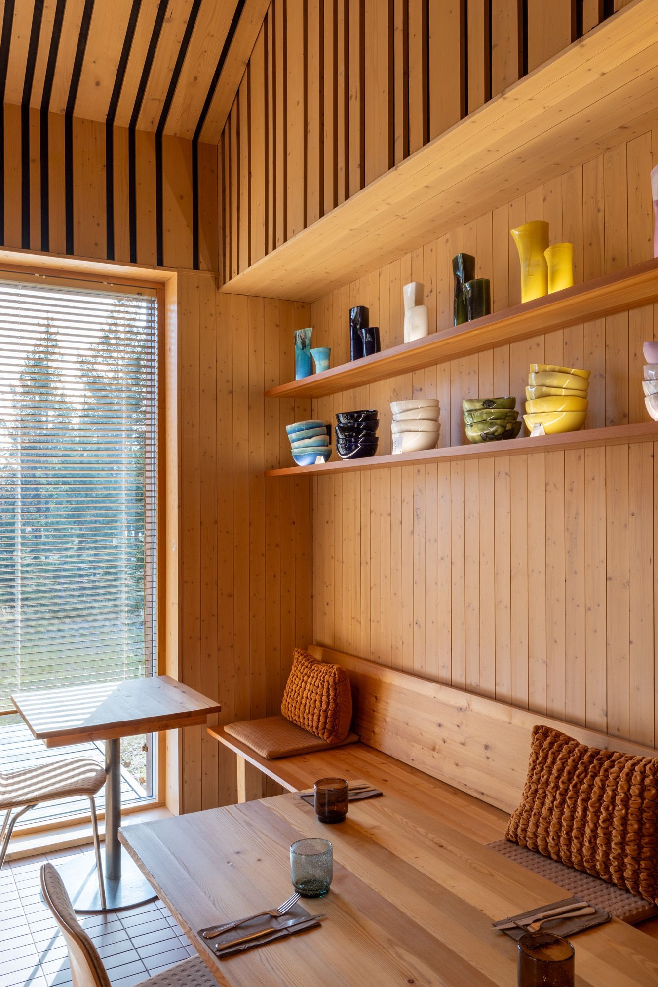 Ravintolanurkkauksessa puinen kiinteä penkki ja avohyllyt. 