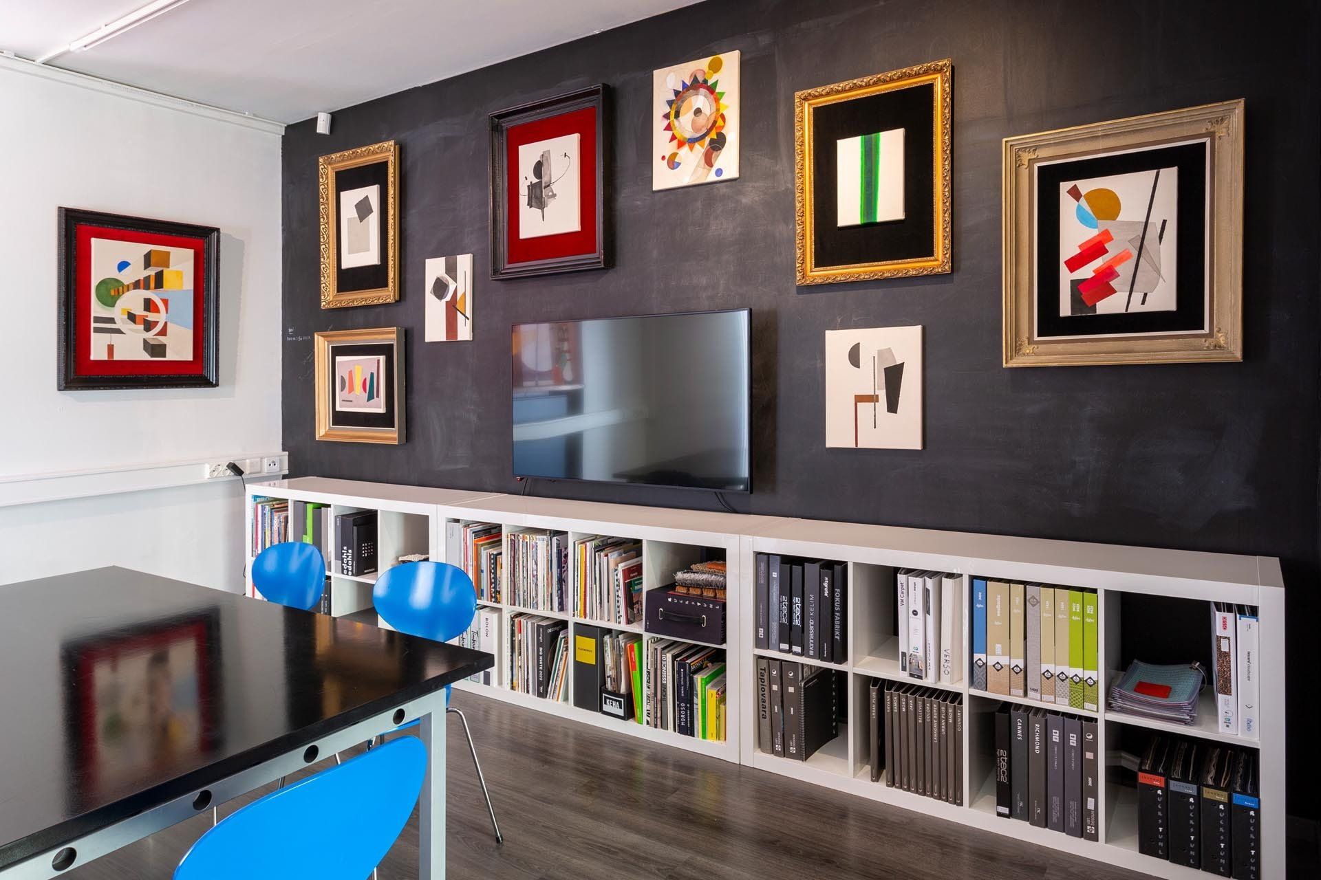 Taidetta suunnittelutoimistossa. TV seinällä taulusommitelma. 