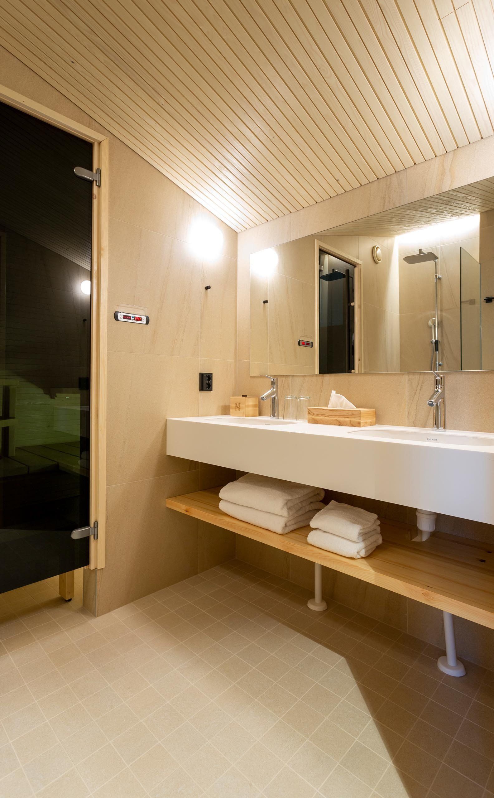 Hotellihuoneen kylpyhuone ja sauna. Hanat Hansgrohe. Corian allastaso. 