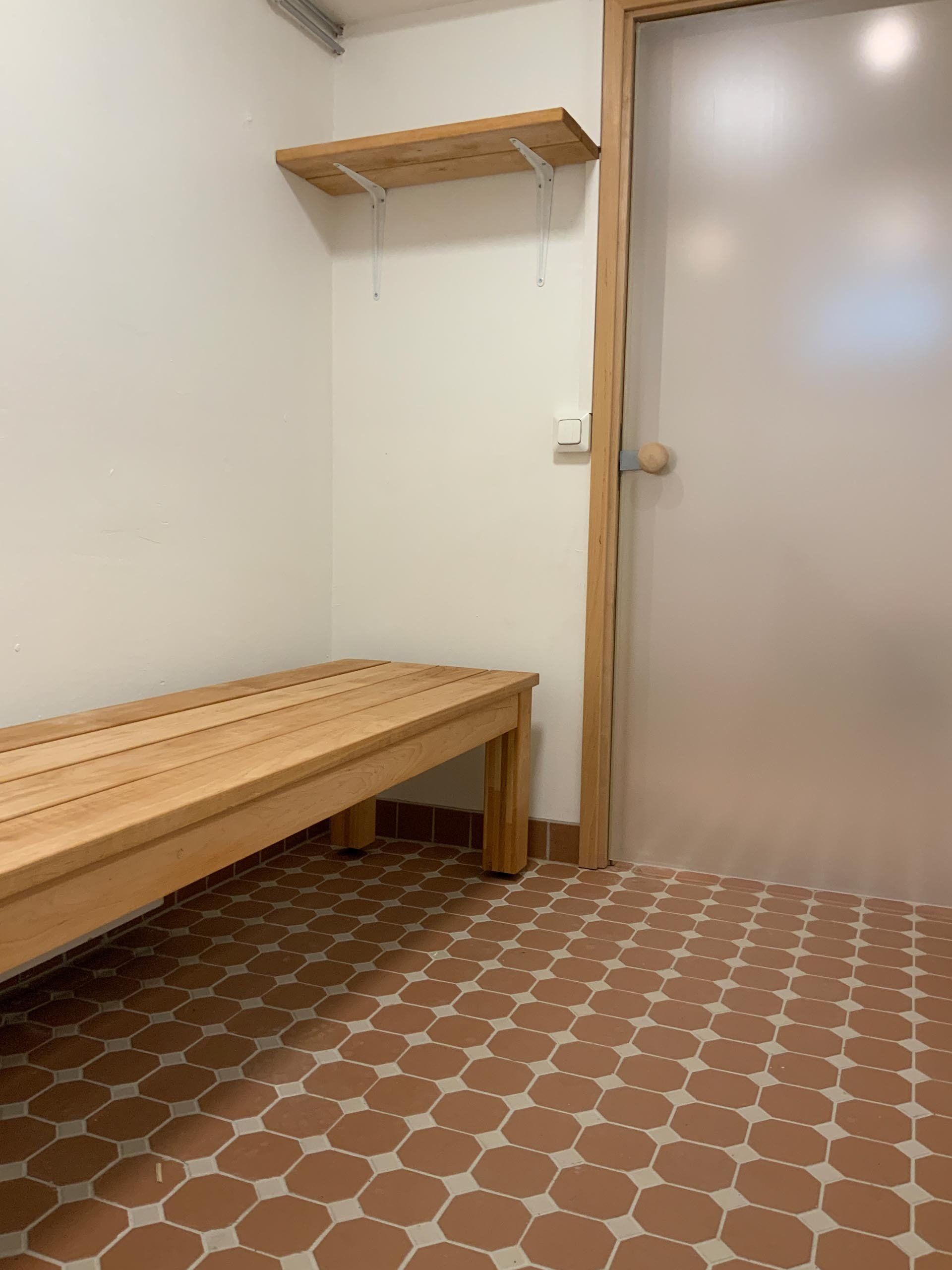 Saunaosaston pukuhuone. Lattiassa  Pukkila Natura kuviolaatta sävyssä terracotta.