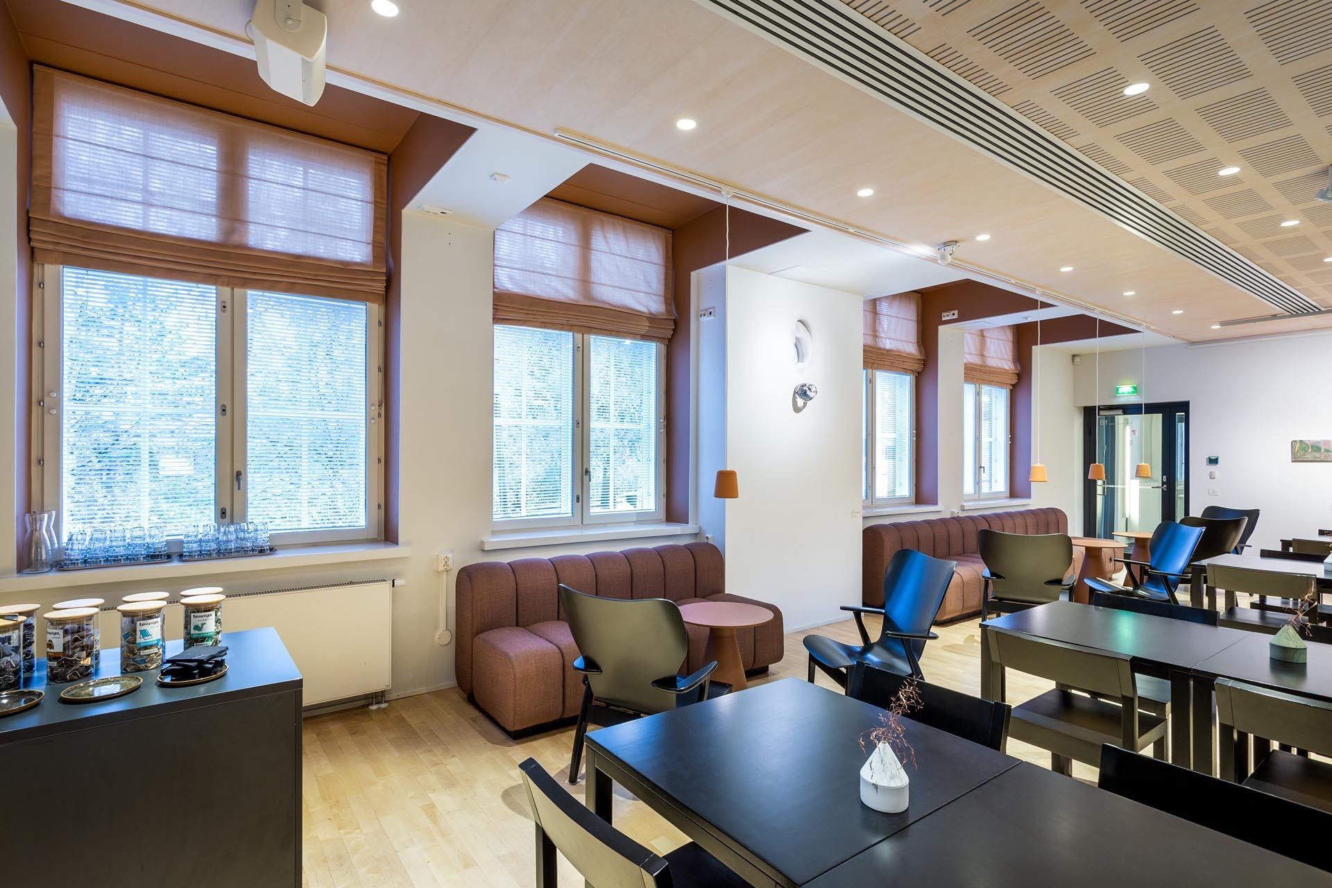 Kahvila-ravintolan sisustus - sohvanurkkaus. Värilliset laskosverhot ikkunoissa. 