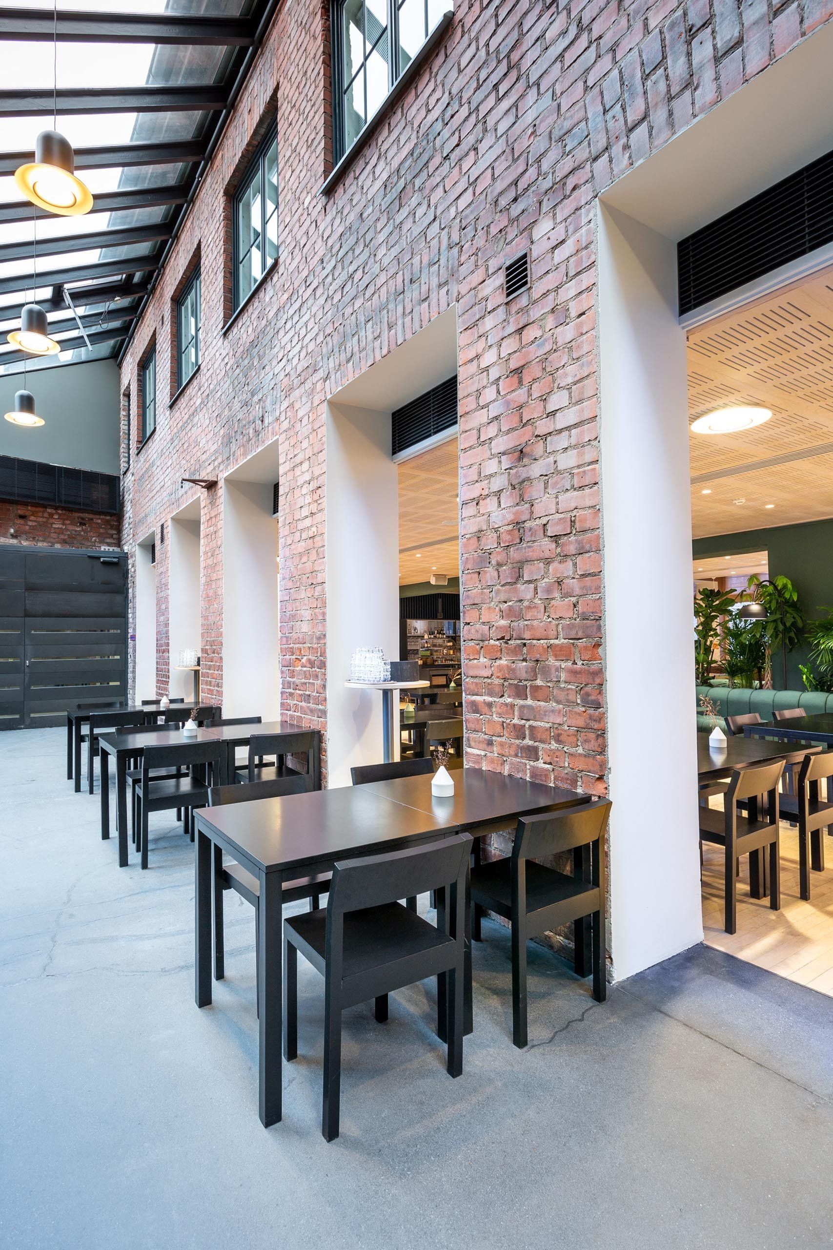 Ravintolasuunittelu. Vanha säilytetty tiiliseinä pöytäryhmien taustalla. 