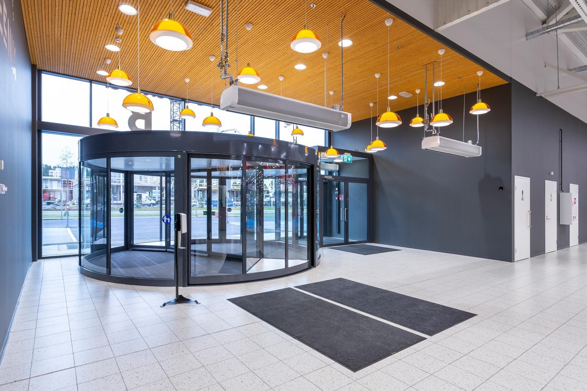 Kauppakeskus sisäänkäynti. Valaisimet Innolux Kuplat ja puuverhoiltu alakatto.