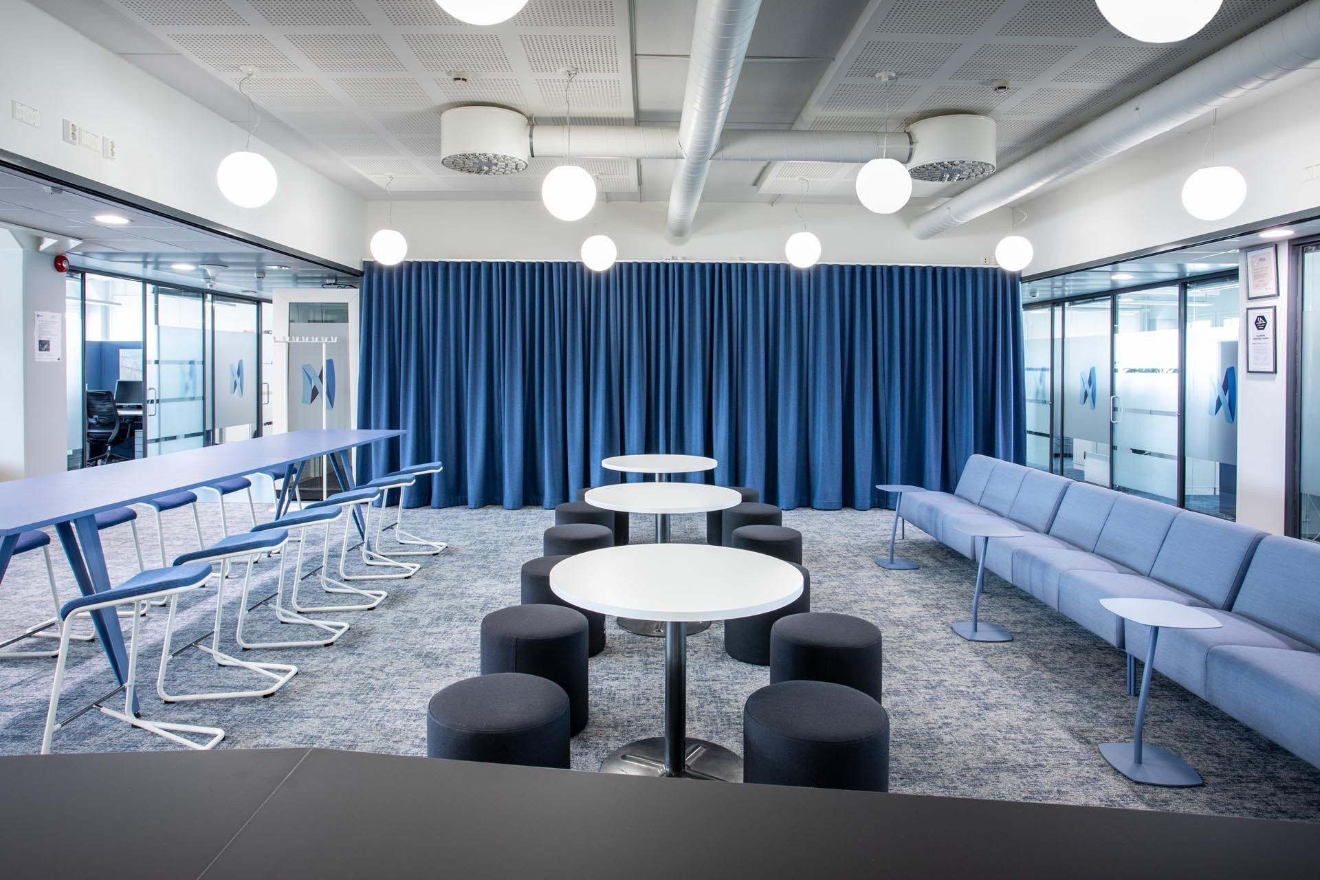 Toimiston taukotilassa Lammhults kalusteet. Siniset sohvaryhmät ja pöytäryhmät. 