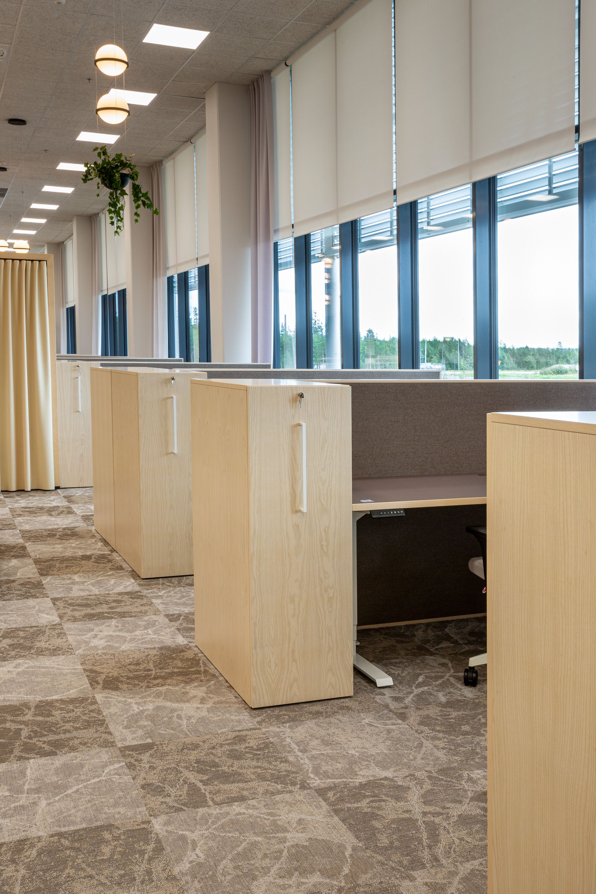 Avotilatoimiston työpiste. Työpisteellä sähkösäätöpöytä linoleum-kannella, verhoiltu sermi ja saarnipuinen toimistokaappi.