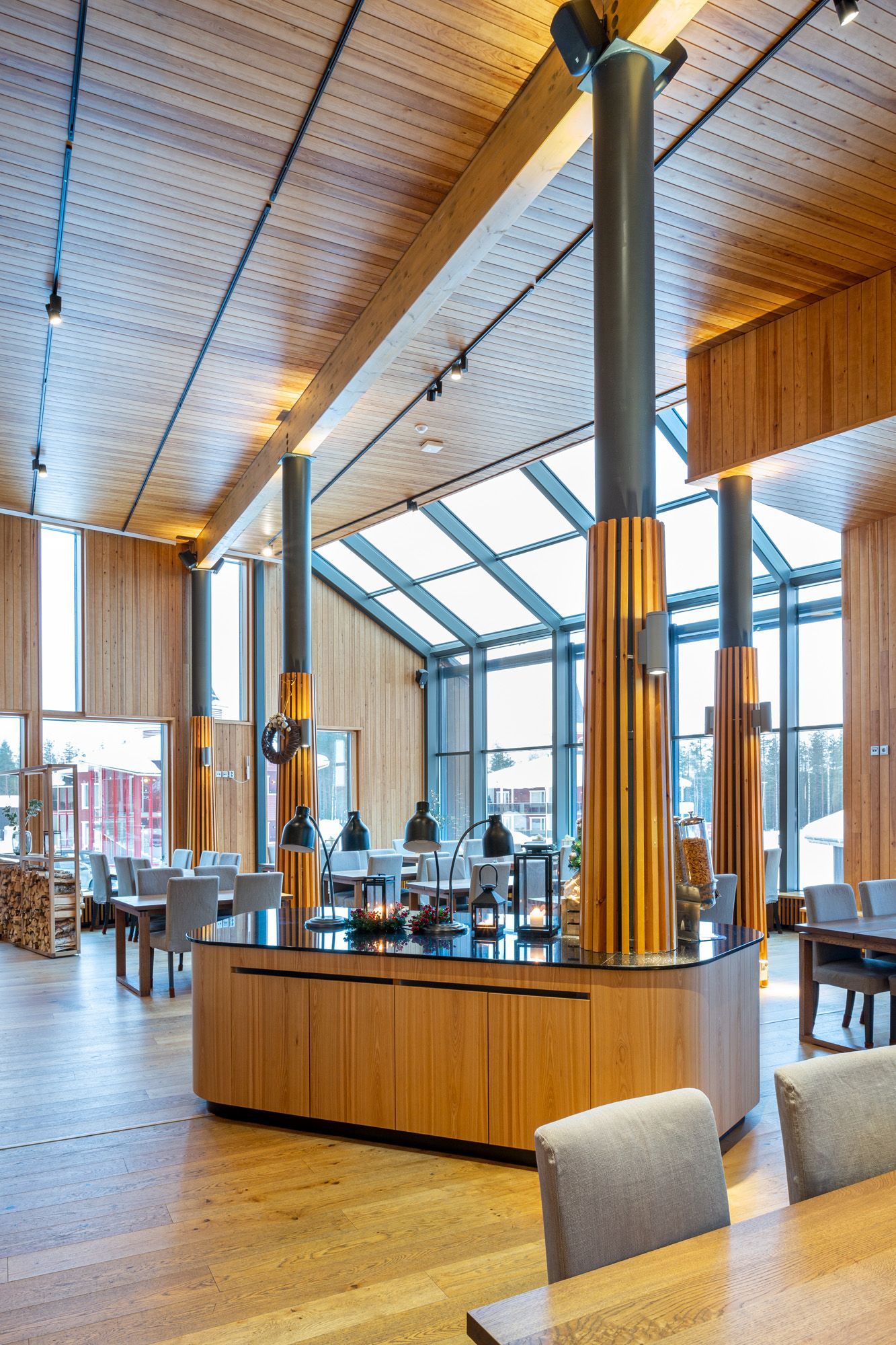 Ravintola napapiirillä. Iso näkymäikkuna. Puurimoitetut pylväät ravintolasalissa. 