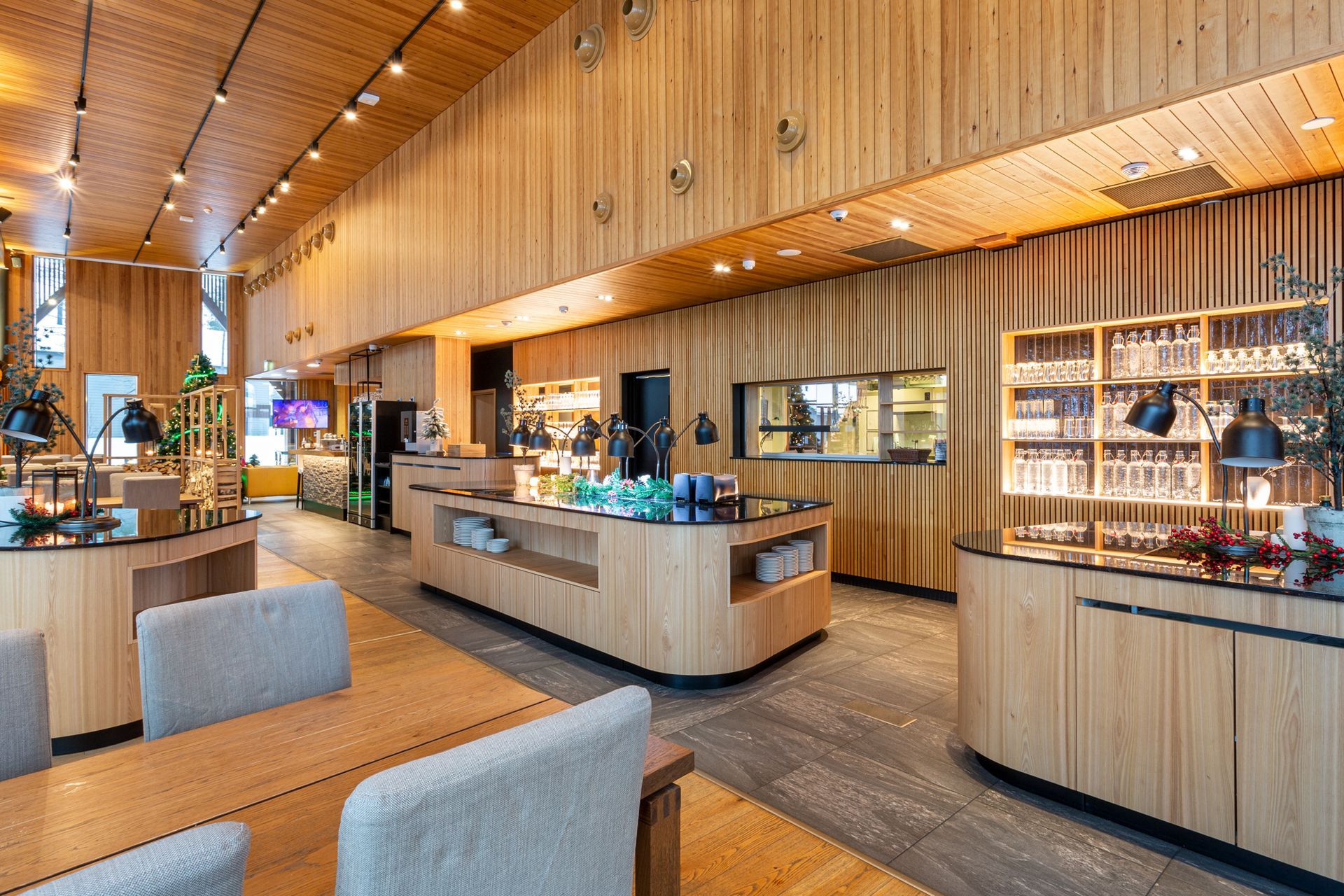 Ravintola Lapissa. Puurimaseinällä led-valaistu lasihyllykkö. Kalusteet ja pintamateriaalit puuta. 