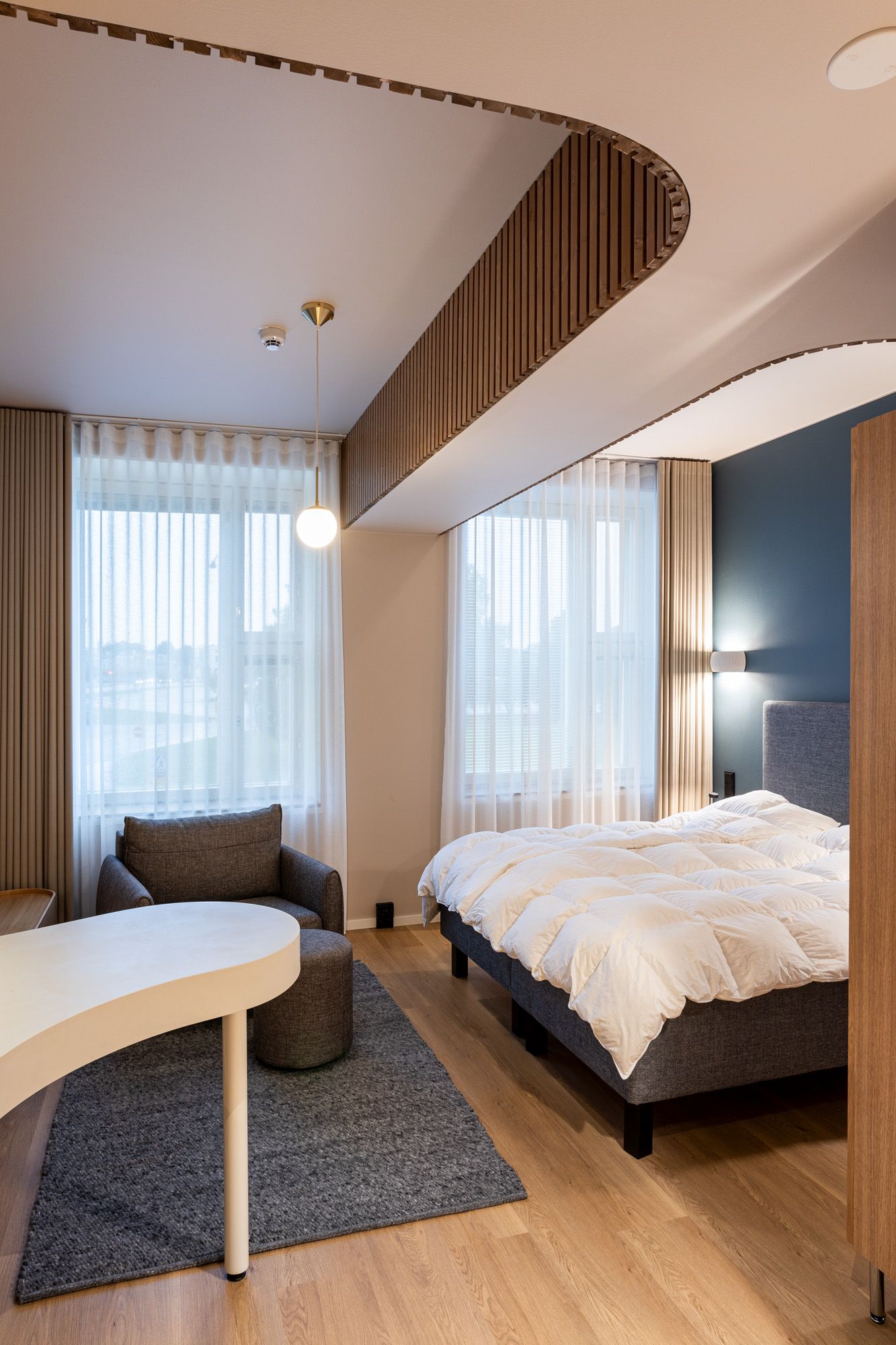 Hotellihuoneen verhosuunnitelma. Ikkunassa sivuverhot ja valoverhot.