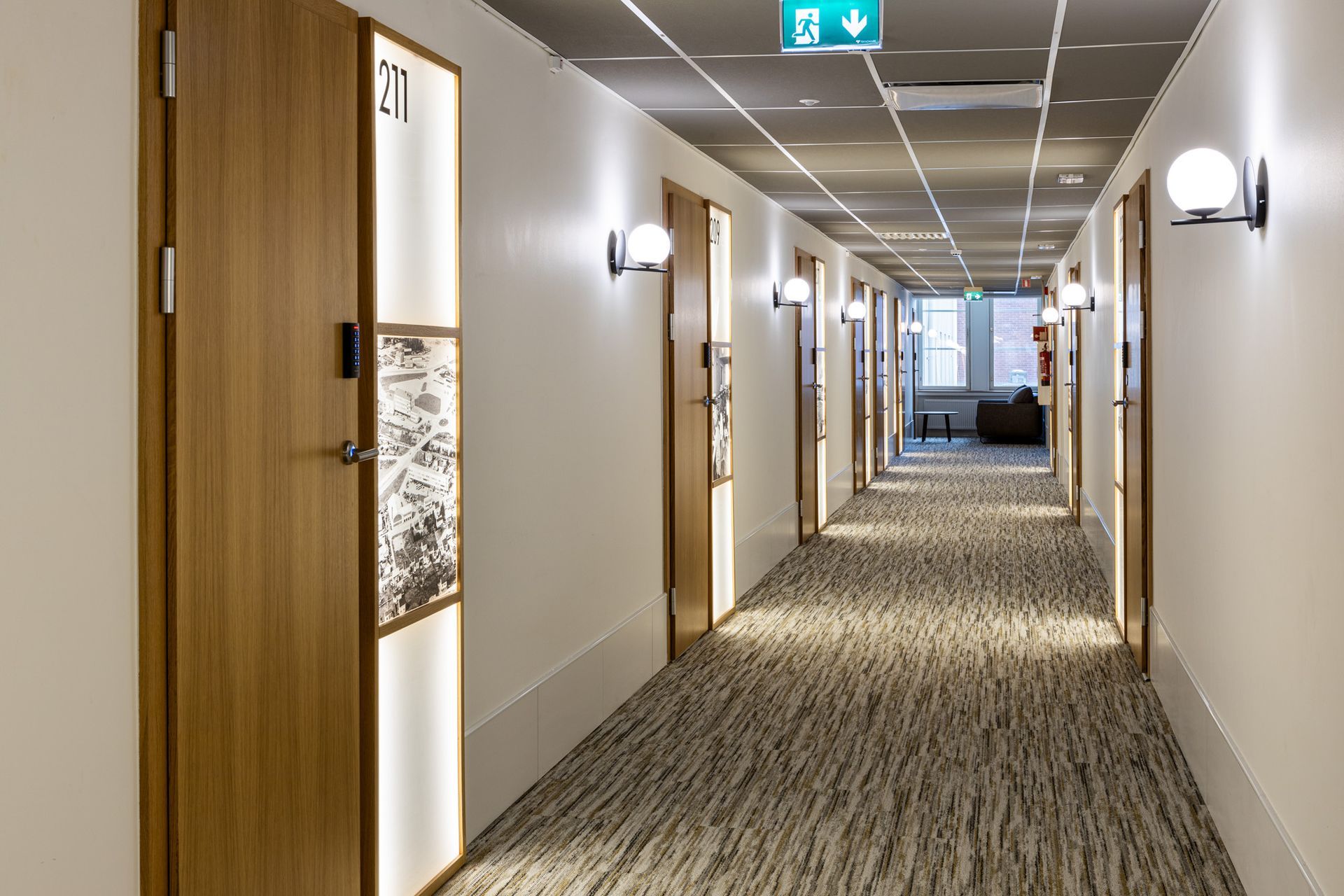 Hotellin käytävän seinävalaisimet ja valaistut huoneopasteet.