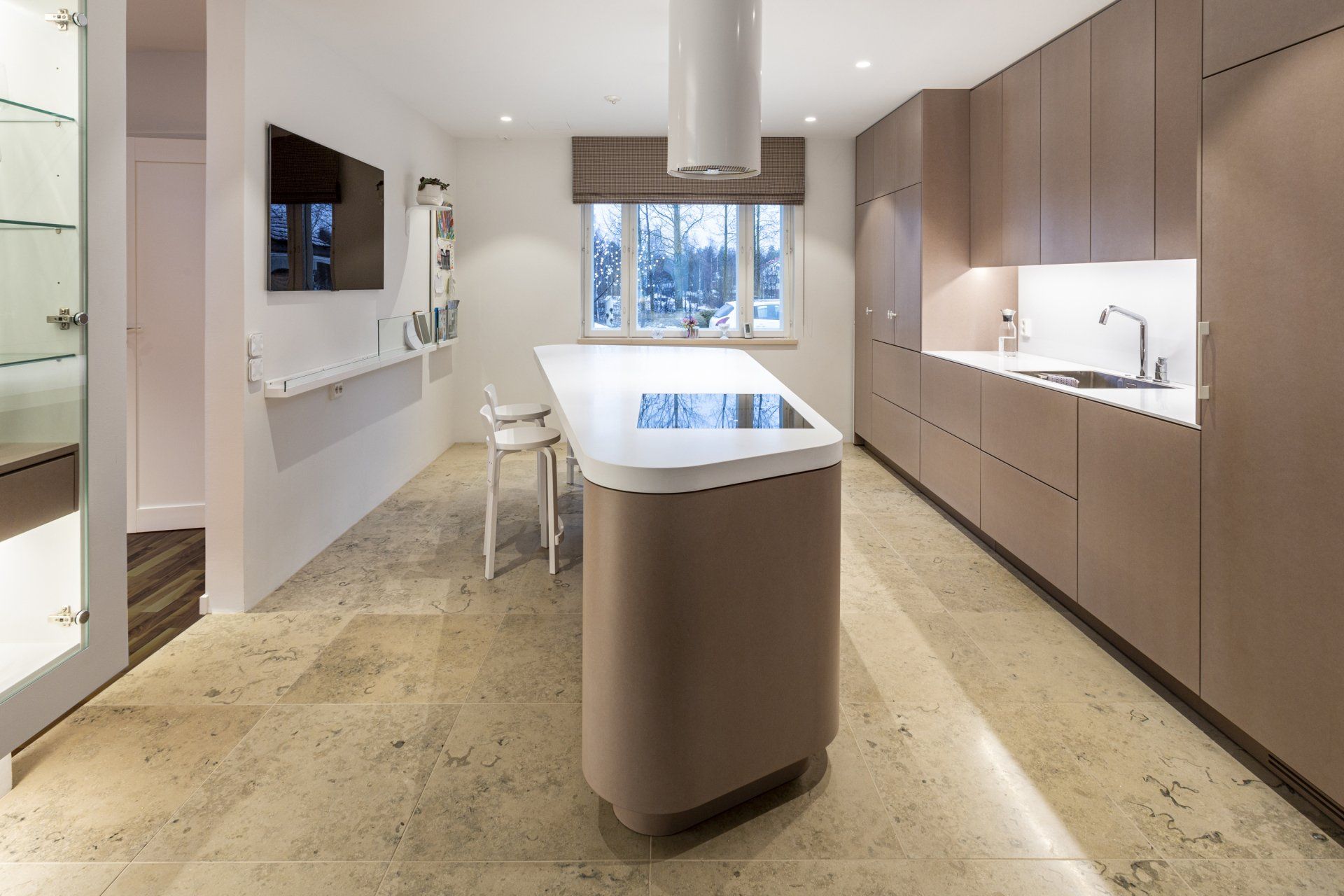 Keittiöremontti. Ruskeat keittiökalusteet ja saareke mittatilaustyönä. Lattian kalkkikivilaatta Tulikivi Jura Beige. 