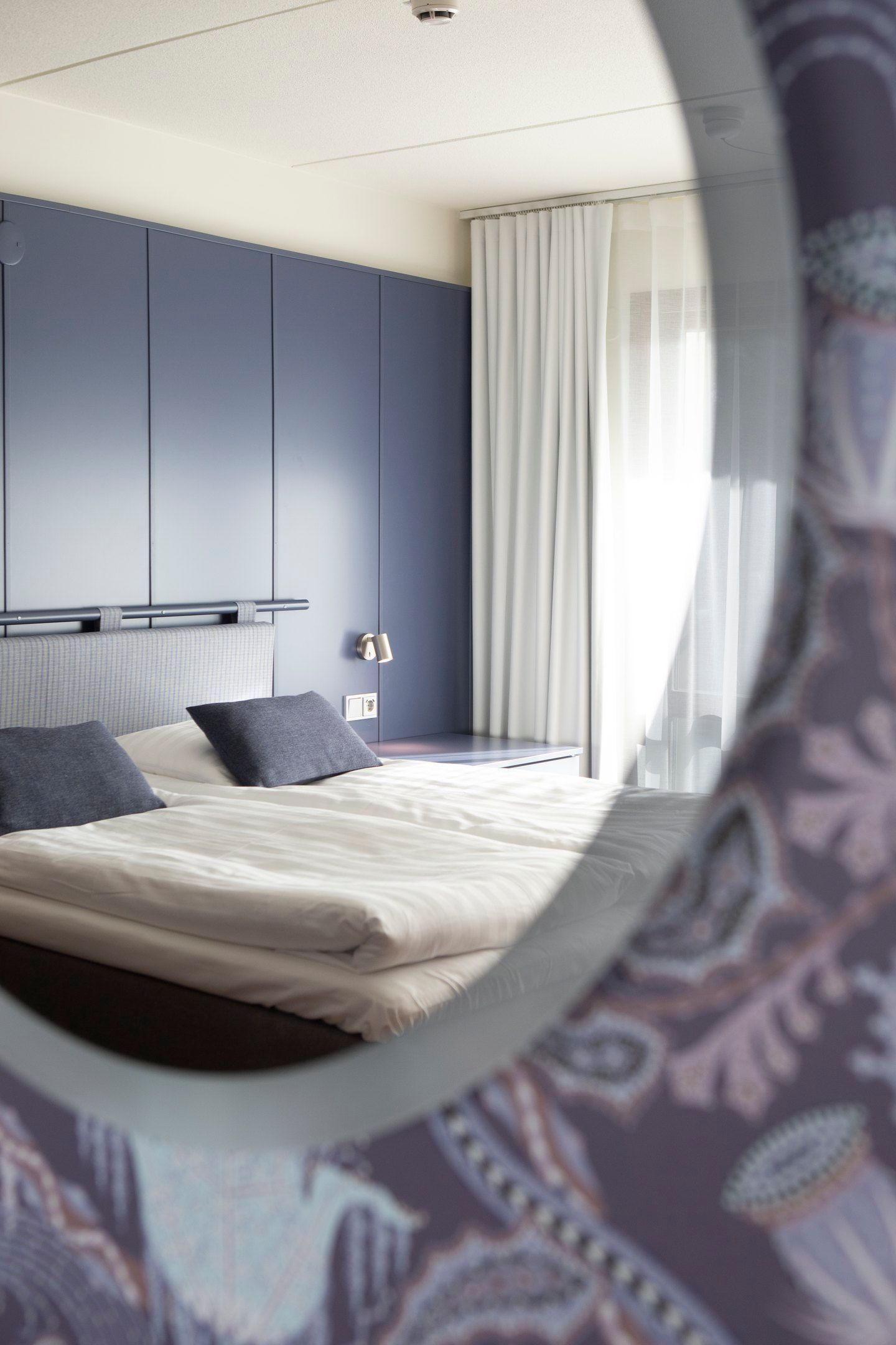 Sininen sängynpäätyseinä hotellihuoneessa.