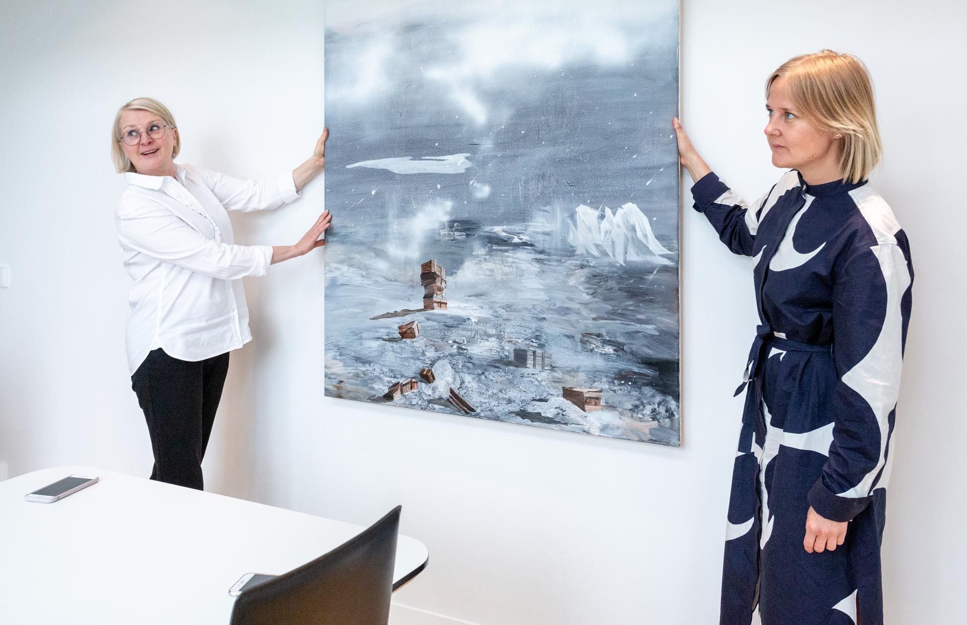 Sisustussuunnittelija Tuula Ylinenpää ja taiteilija Hanna Kanto ripustamassa taideteosta. 