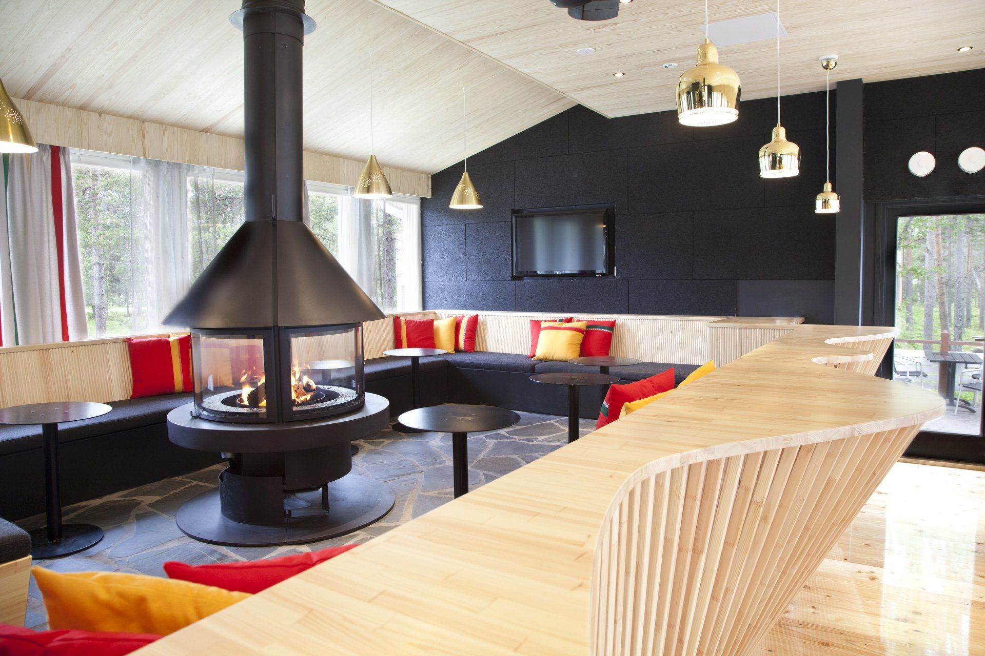 Lappihenkinen lounge-alue ravintolassa. Takkaa kiertää puusepällä teetettu istuinkaluste.