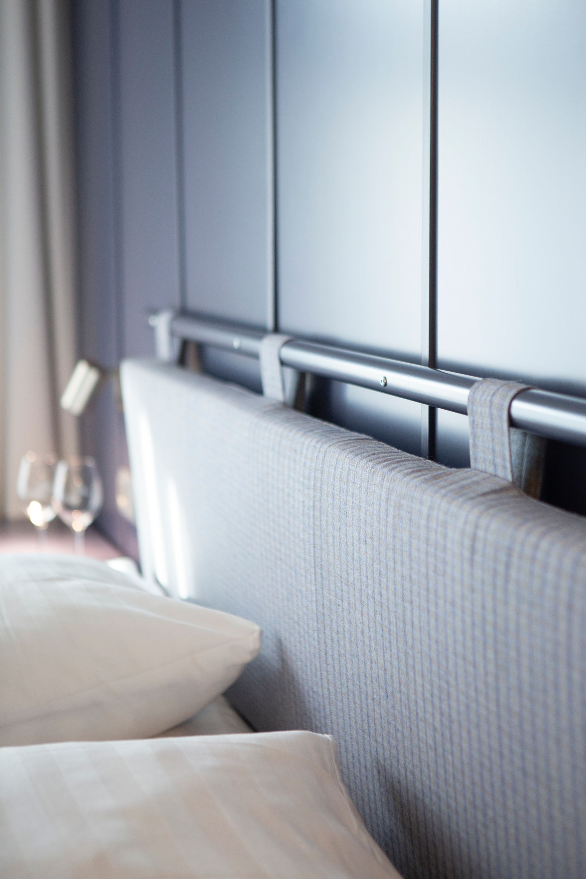 Hotellihuoneen sängynpäätysuunnitelma. Tankoon ripustettu verhoiltu sängynpääty. Verhoilukangas Kvadrat Recheck.