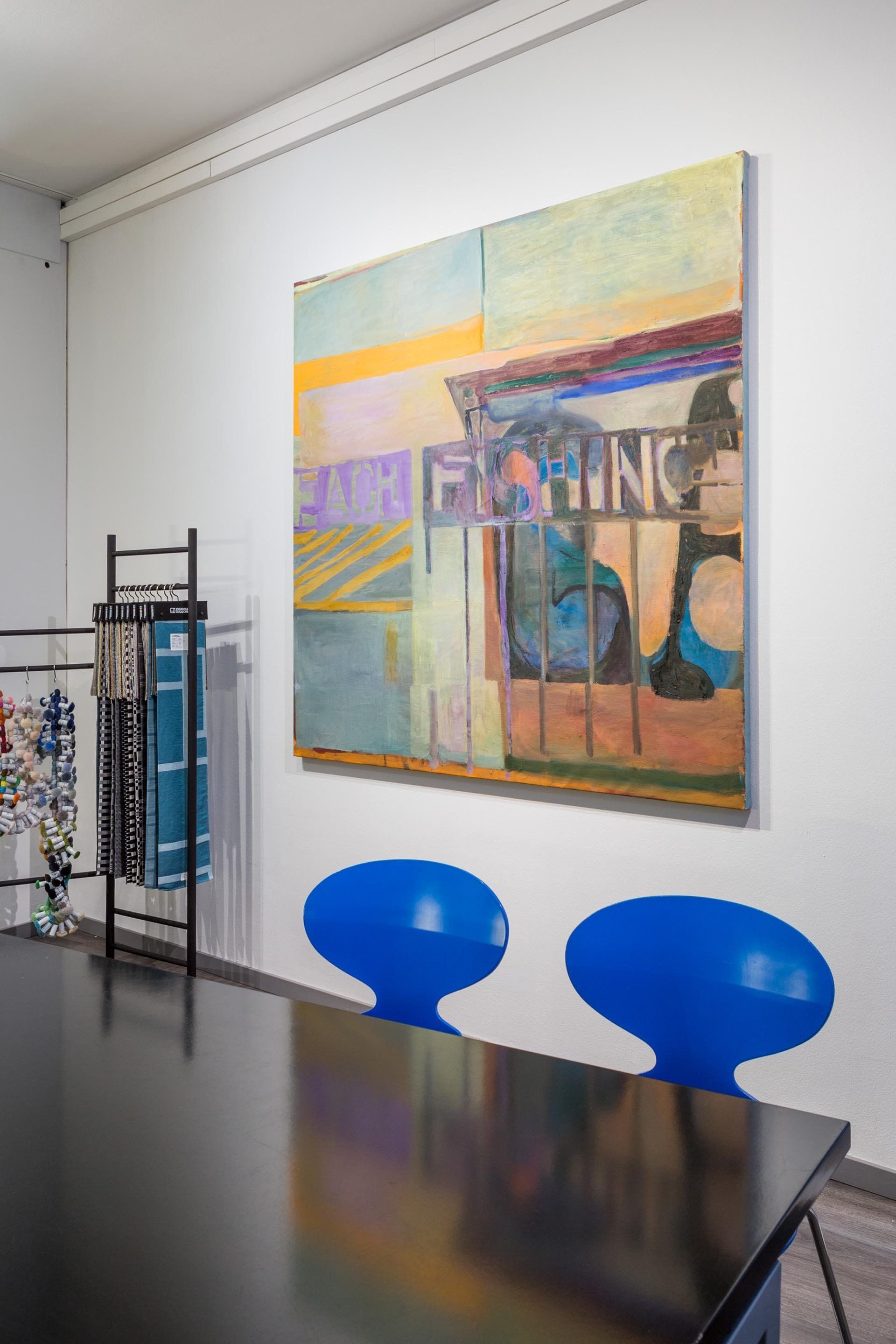 Tuuli Kerätär taideteos seinällä. Vieressä tekstiilinäytteet. 