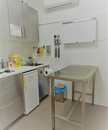 Una cocina con gabinetes de acero inoxidable, un fregadero y una mesa.