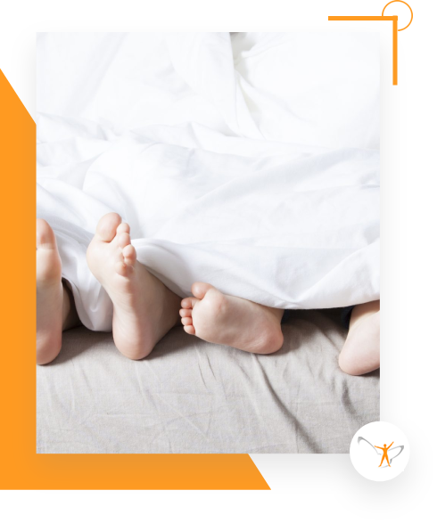 Kinderfüße schauen unter Bettdecke hervor