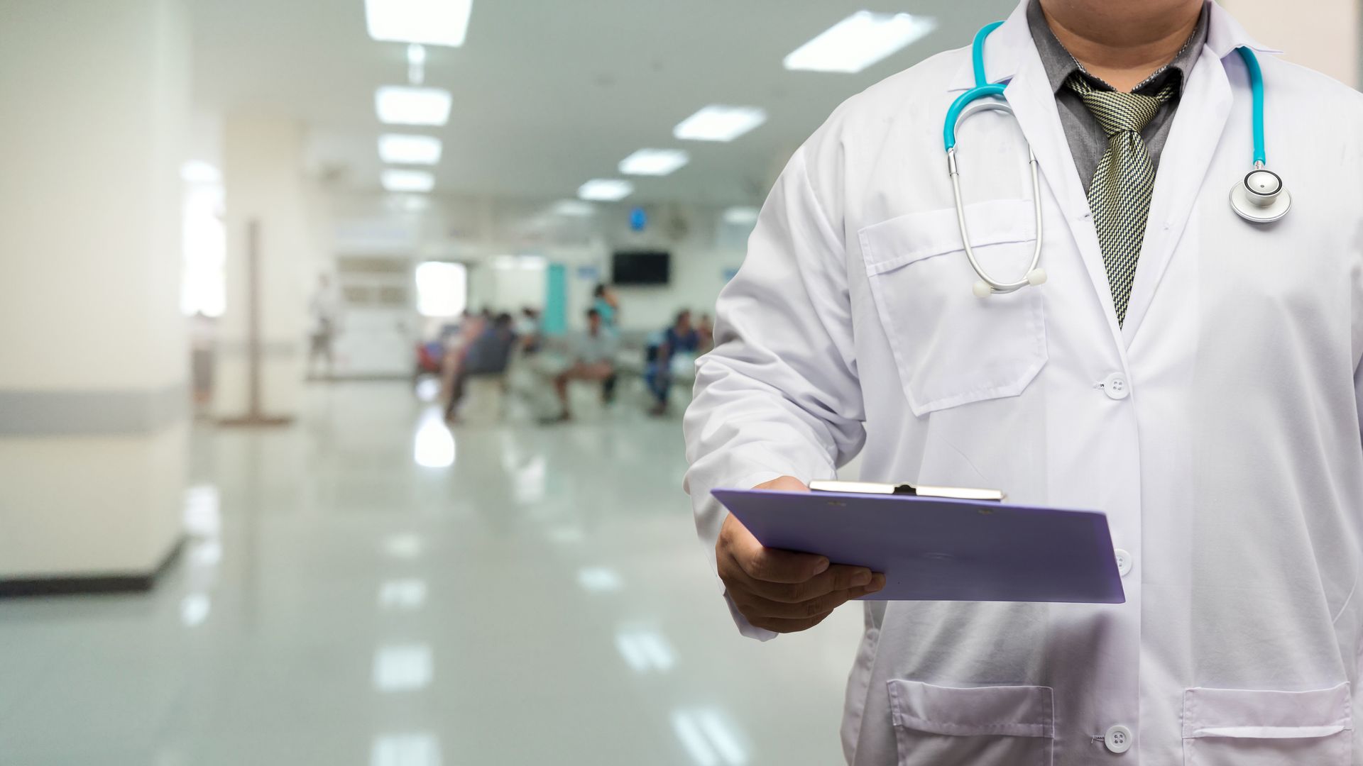 Un chirurgien marche dans le couloir d'un hôpital et porte un bloc-notes