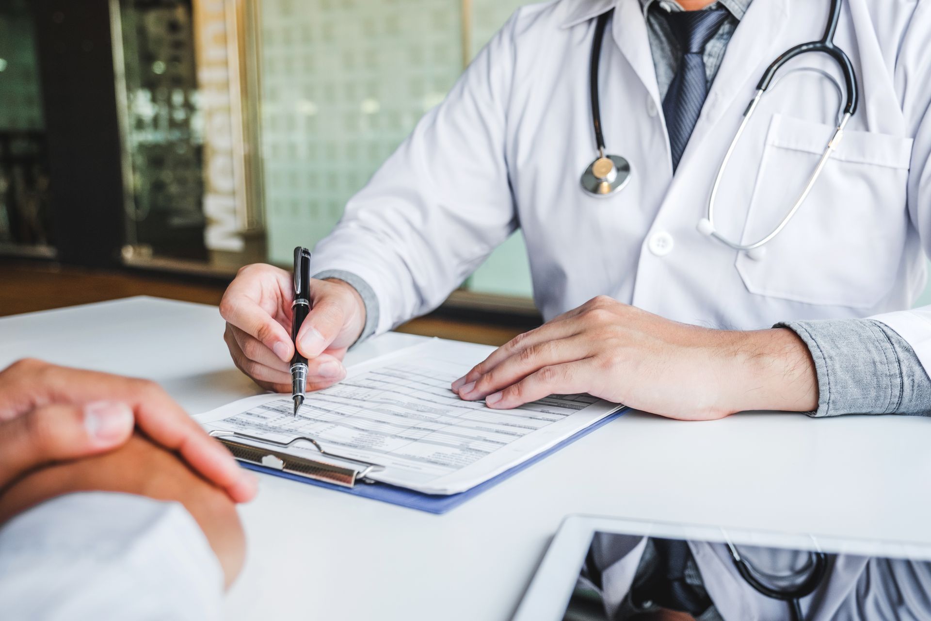 Un médecin prend des notes sur un bloc-notes lors d'une consultation avec un patient