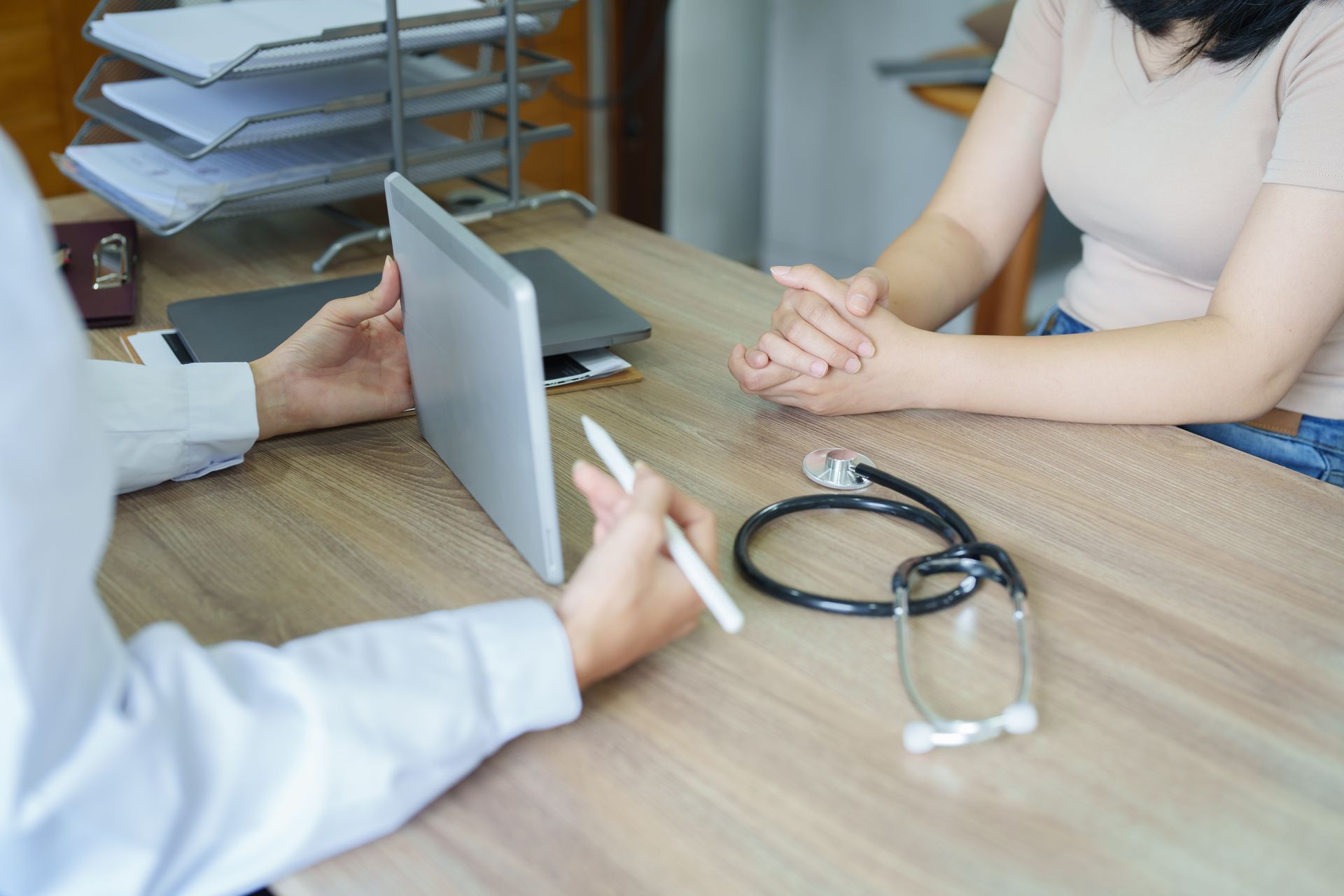 Un médecin en pleine consultation, un ordinateur portable et un stéthoscope sont posés sur le bureau