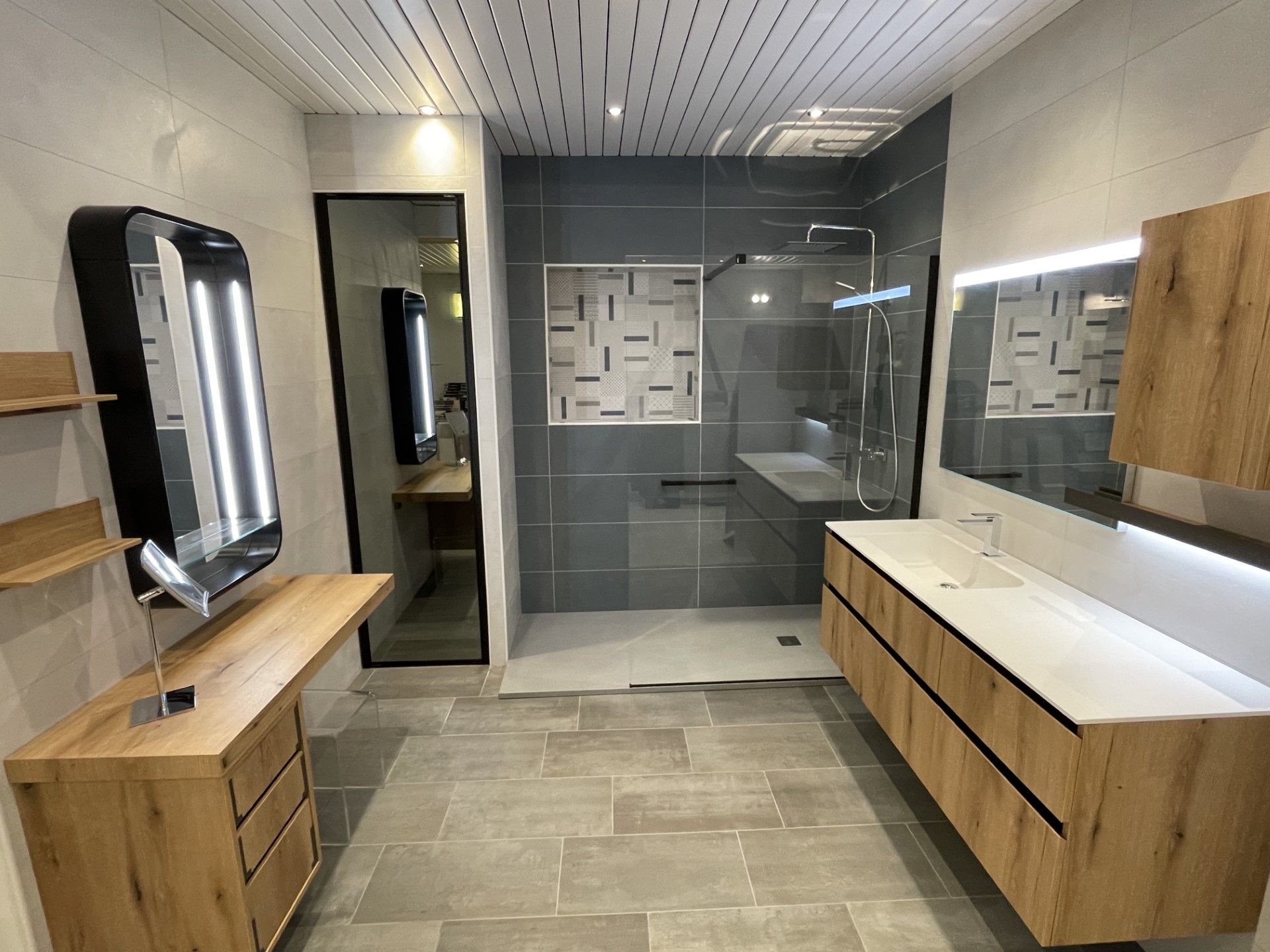 Salle de bains moderne avec meubles-lavabos en bois, carrelage gris et cabine de douche en verre