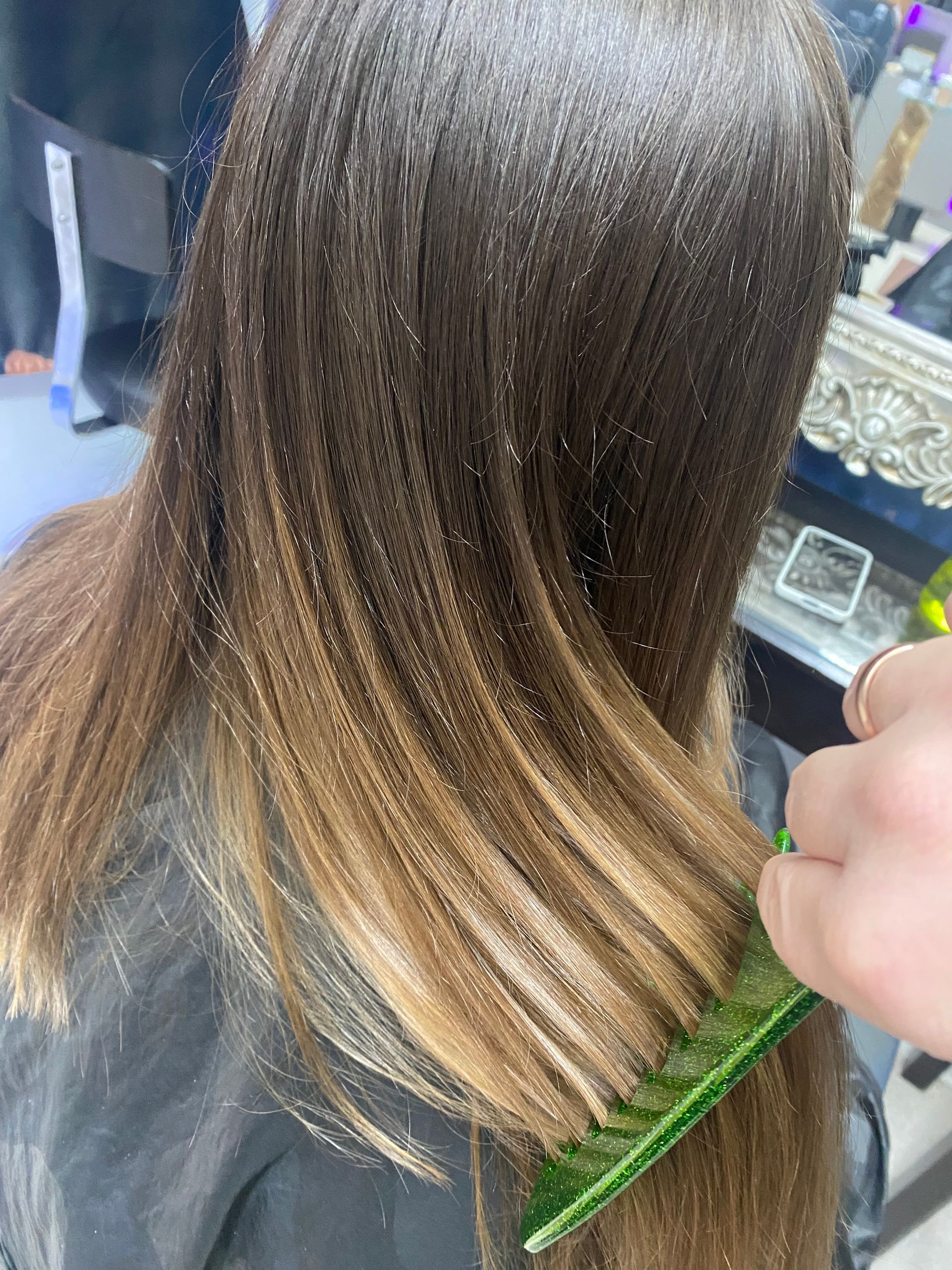 Eine Frau lässt sich von einem Friseur die Haare kämmen.