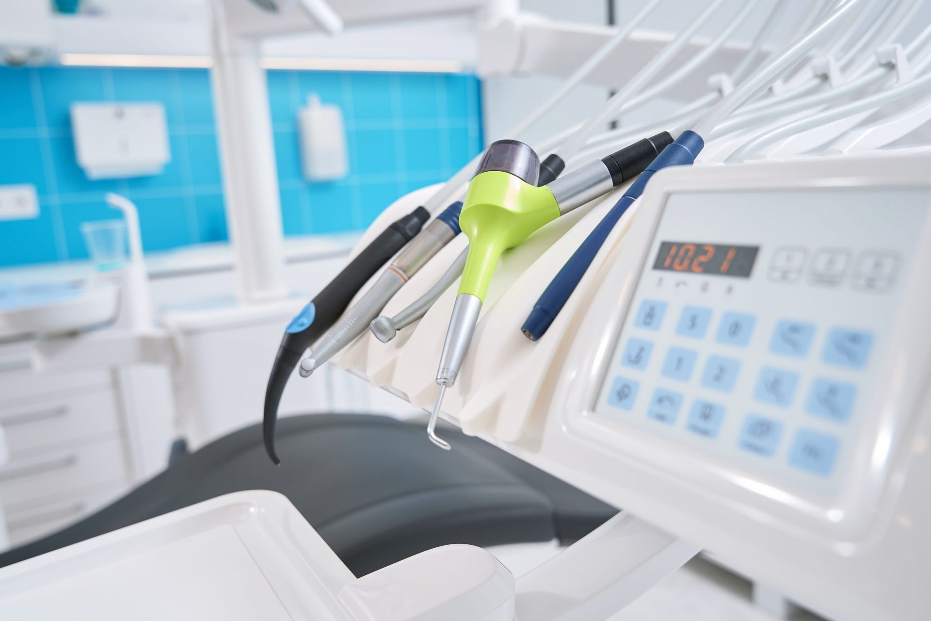 Sillón de clínica dental con instrumentos blancos y verde lima y un panel de control digital
