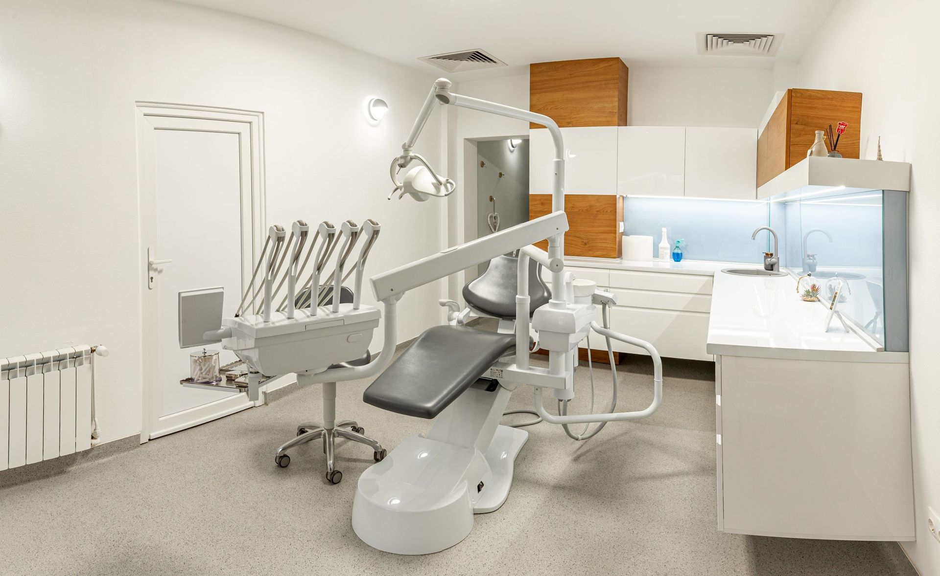 Clínica dental moderna con sillón, lámparas de techo y armarios blancos