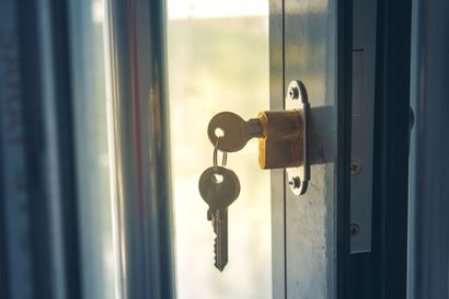 Clé insérée dans la serrure d'une porte vitrée.