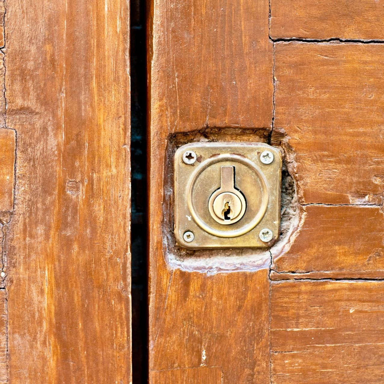 Serrure ancienne insérée dans une vieille porte en bois.