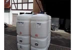 Ein Stapel weißer Plastiktanks, die übereinander auf einem Bürgersteig stehen.