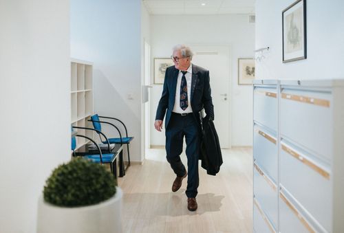 Dr. Rainer Hildebrand in Anzug und Krawatte geht durch einen Flur.