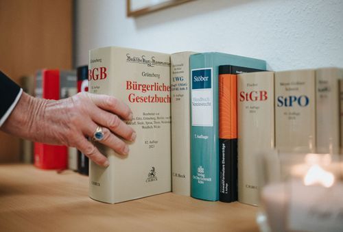 Dr. Rainer Hildebrand greift nach einem Buch auf einem Tisch.